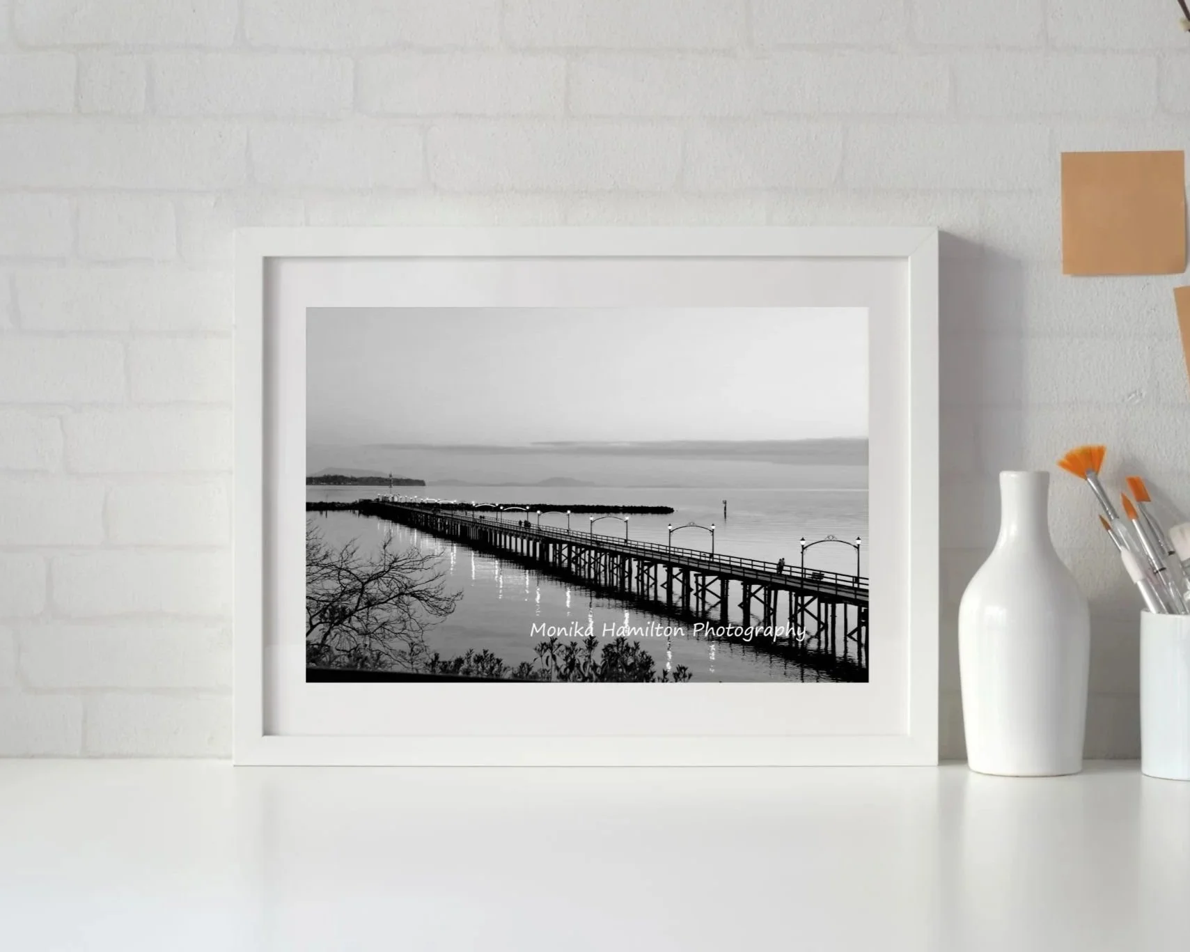 The White Rock Pier in Black and White - the iconic pier's lights reflect on the calm water. People are enjoying their summer evening stroll. This is one of my most popular prints. 