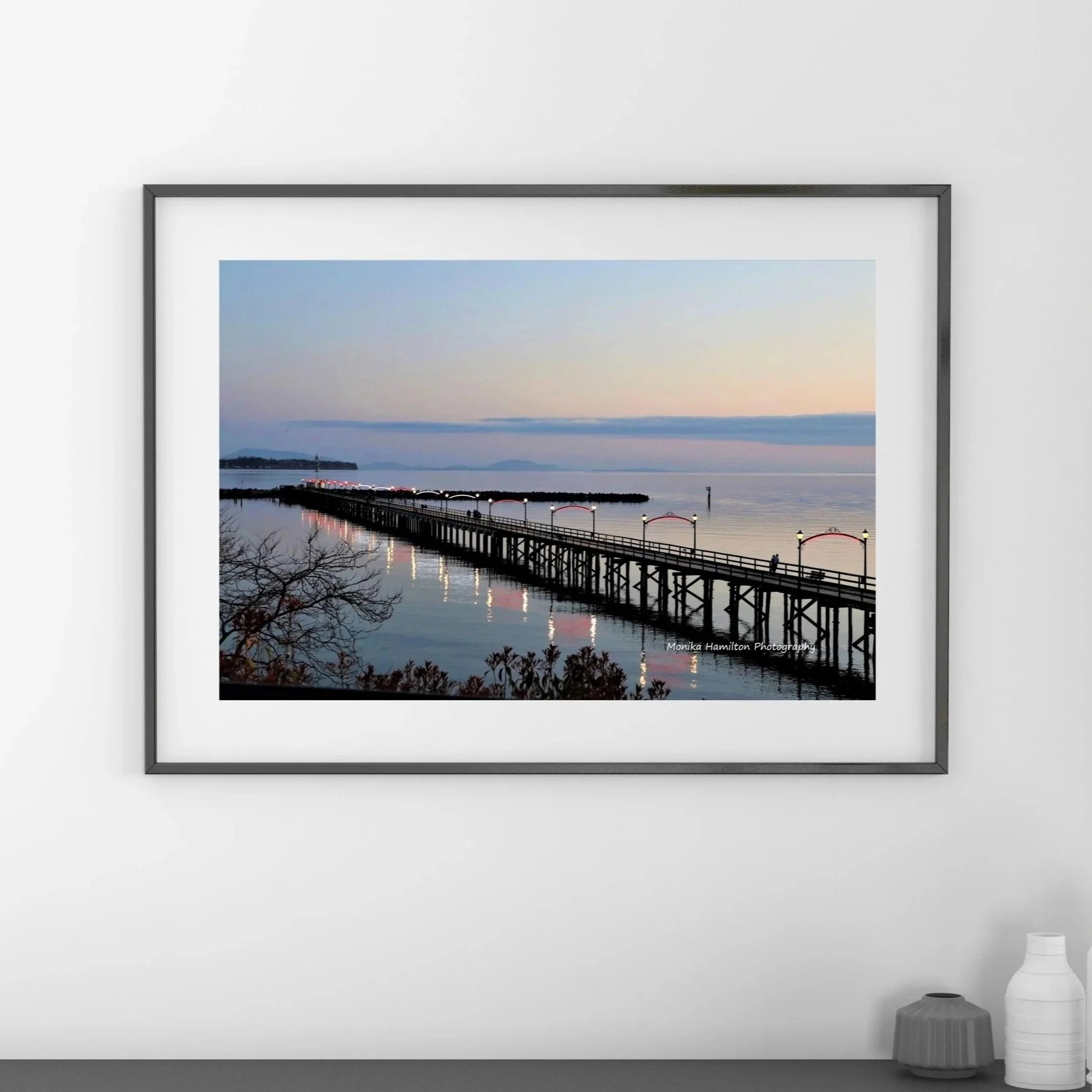 The White Rock Pier at Sunset - the iconic pier's lights reflect on the calm water. This is one of my most popular prints. Available as a canvas or photo print. Choose between colour or black and white. Monika Hamilton Photography