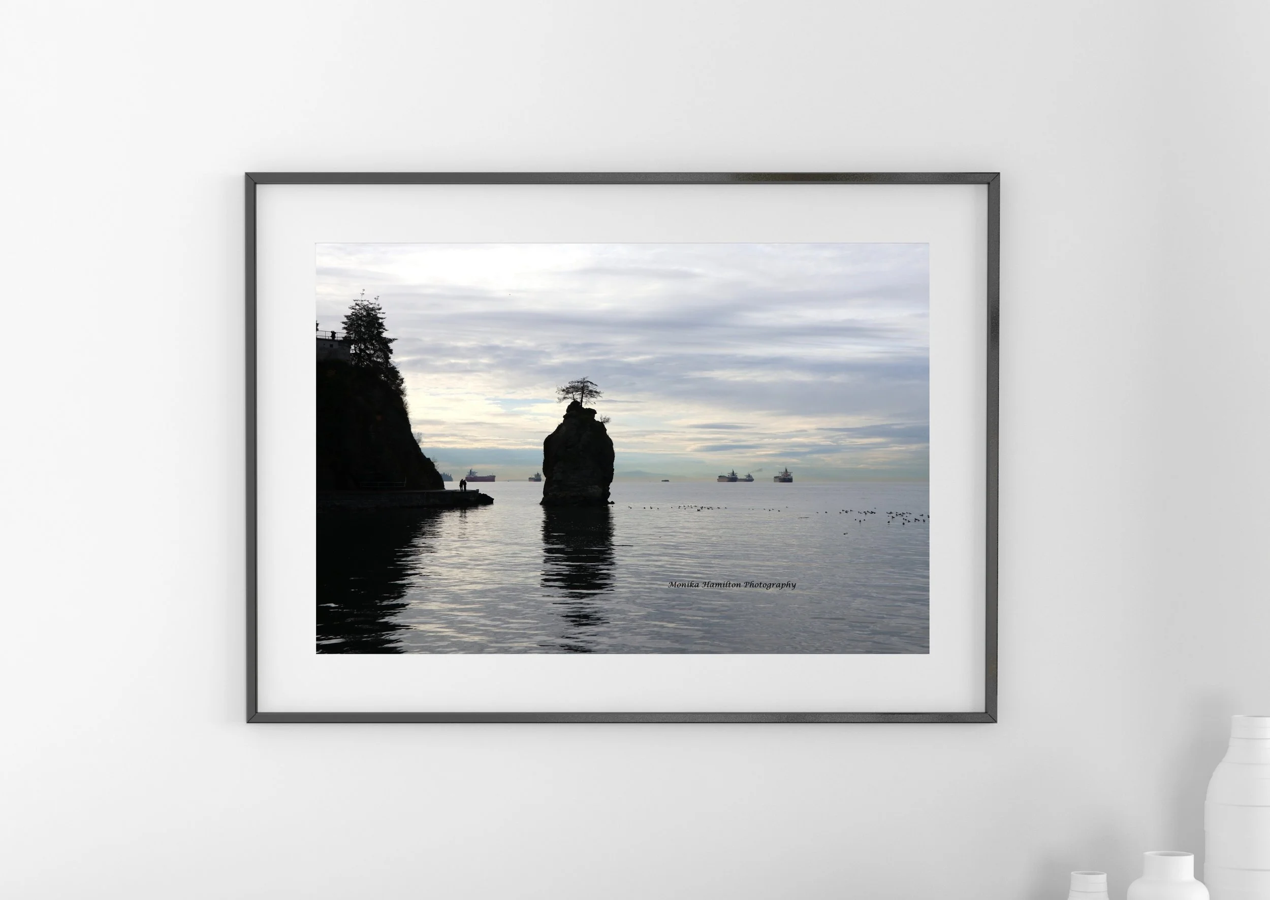 Majestic Siwash Rock by the Stanley Park Seawall in Vancouver, British Columbia, reflected in calm water, with ships in the distance. Monika Hamilton Photography