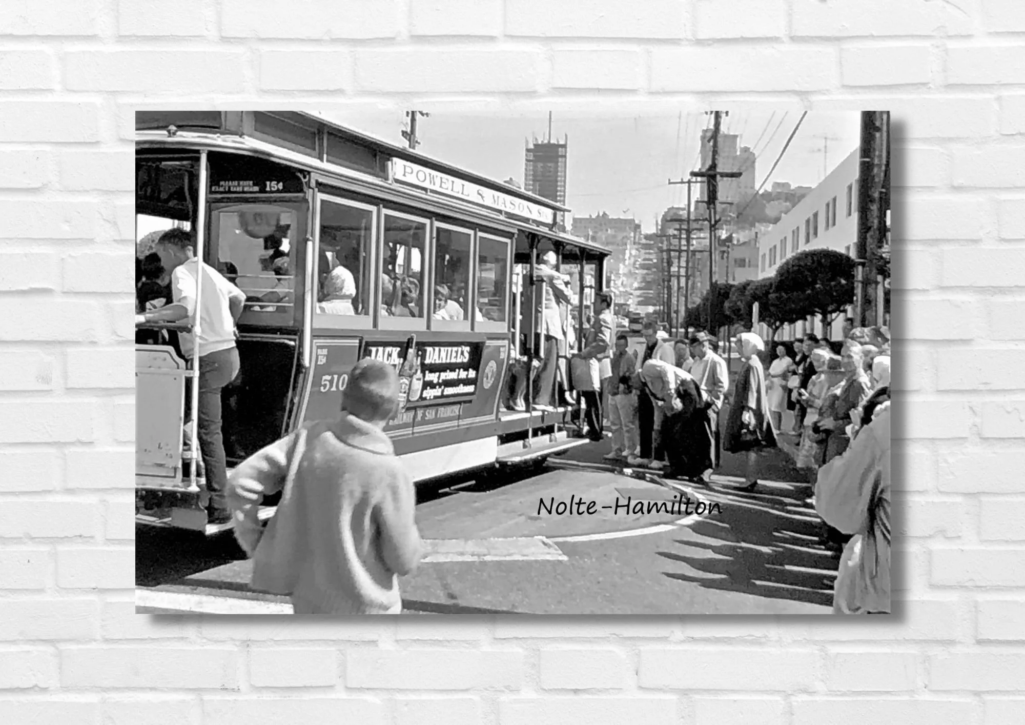 Vintage photo of a trolley street car in San Francisco, California. The cable car is labeled Powell Street. People are getting on and off, with some waiting in line. This is an original city street scene taken by my dad in the 1960s.