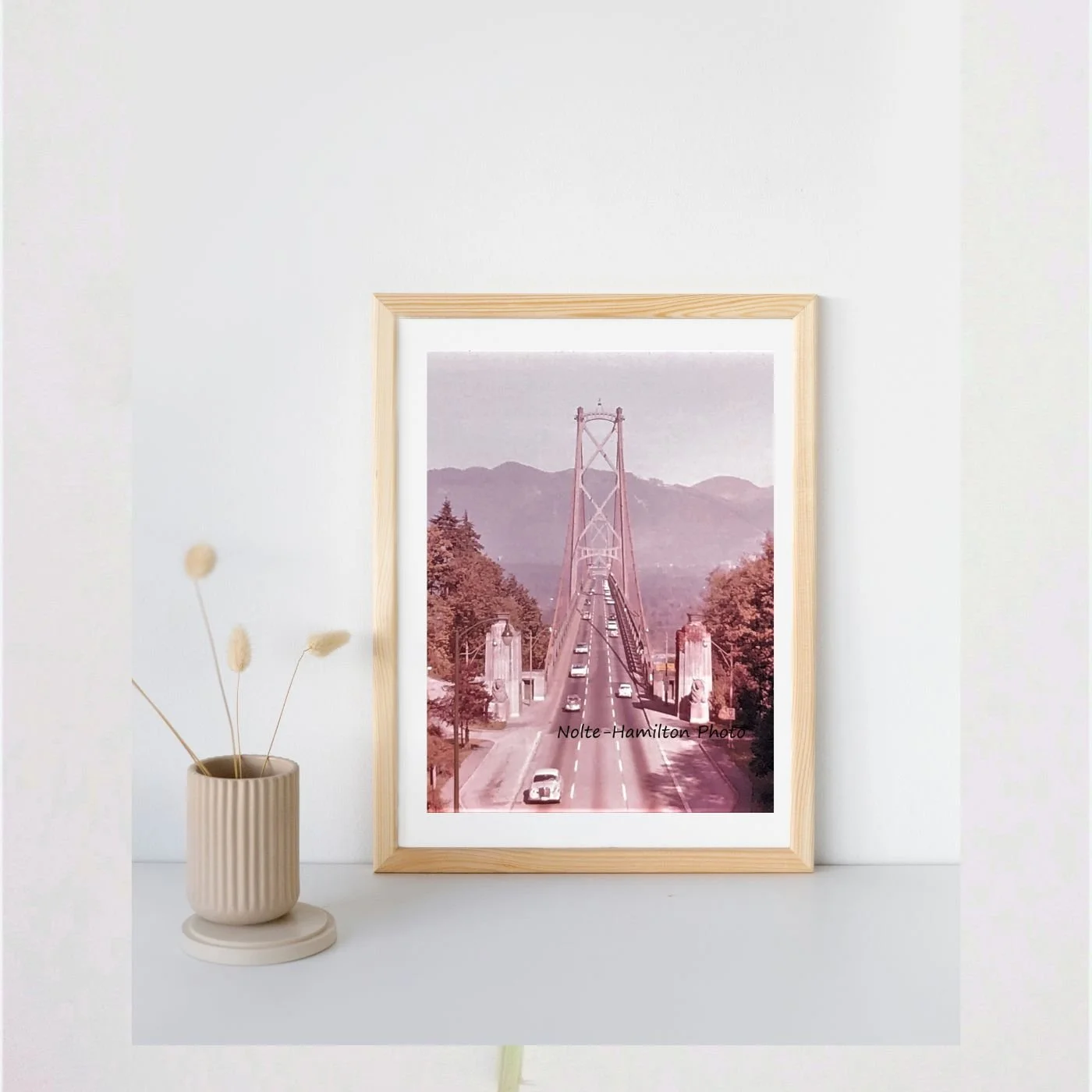 Vintage photograph of the Lion's Gate Bridge in Vancouver, British Columbia. Classic cars drive across the bridge. Lion sculptures adorn the sides of the bridge entrance. My dad took this photograph in the 1960s. 