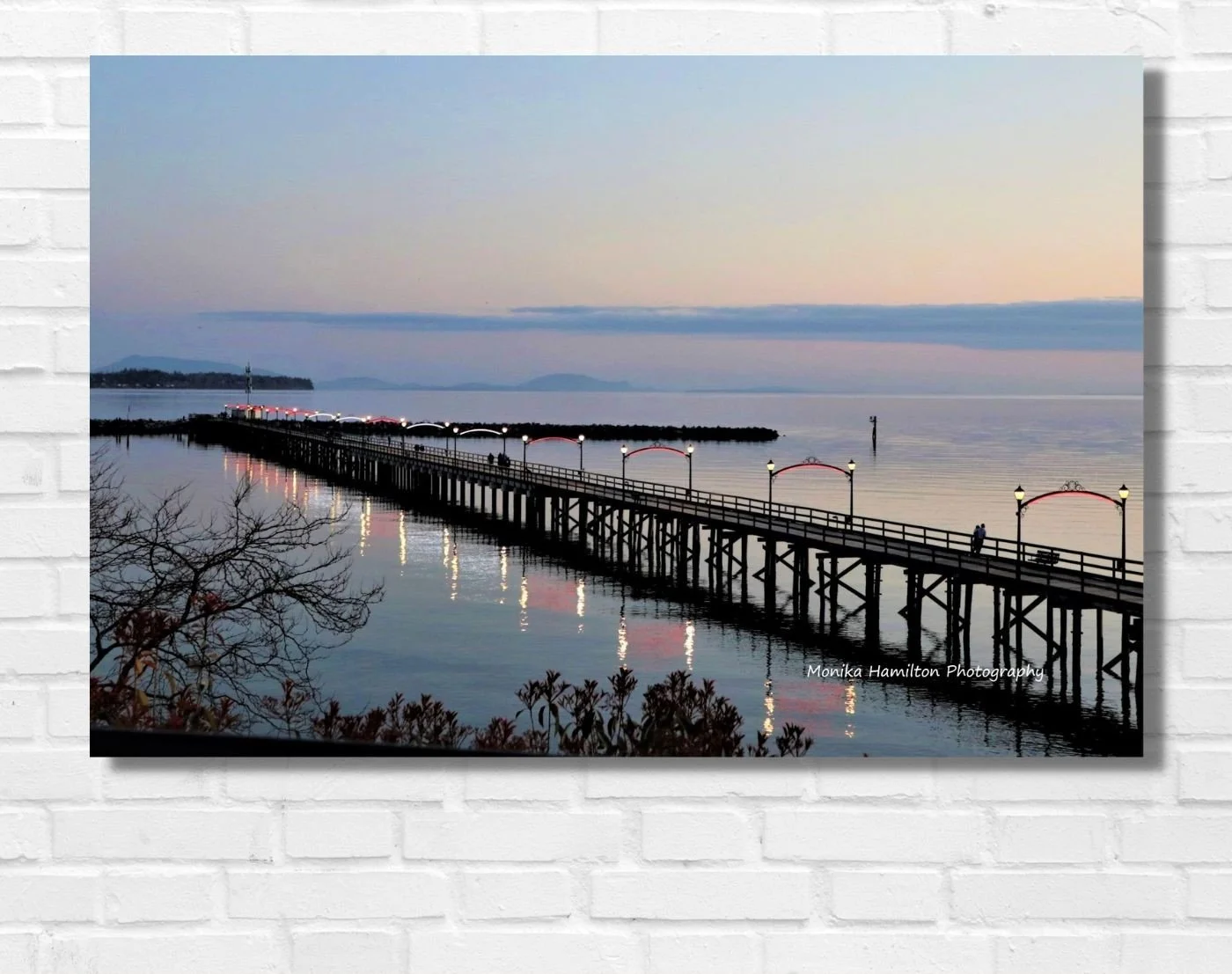 The White Rock Pier at Sunset - the iconic pier's lights reflect on the calm water. People are enjoying their summer evening stroll. Available as a canvas or photo print. Monika Hamilton Photography