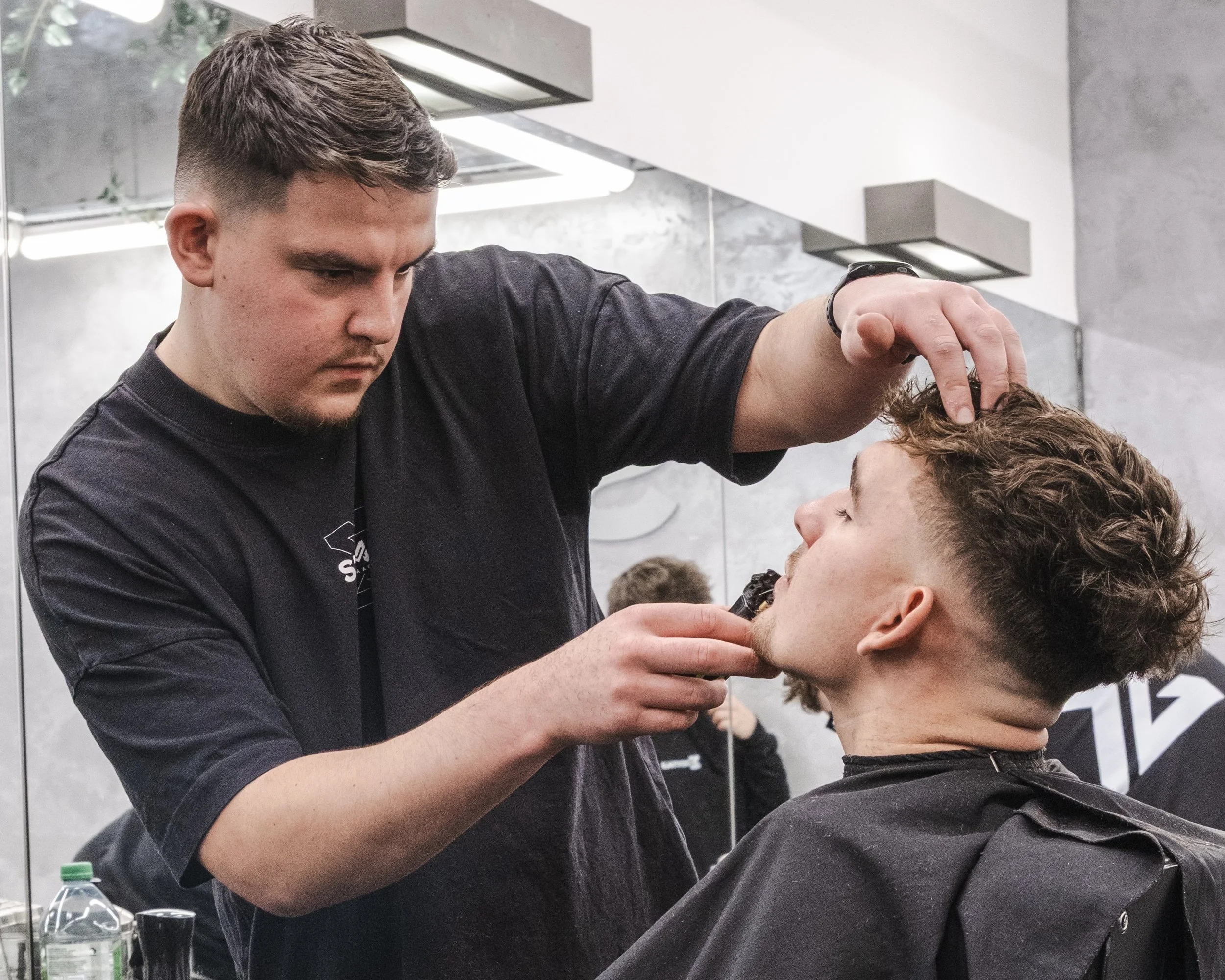 Barber trimming a customer's beard in a modern salon