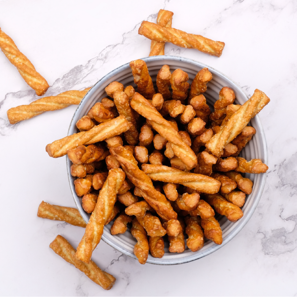 A bowl of golden French fries and small fried potato bites on a white marble surface.
