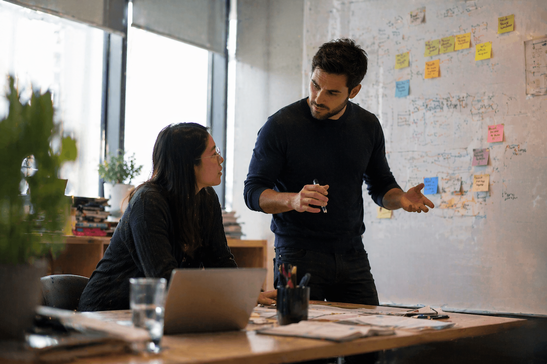 Fractional CPO working with a founder at a whiteboard reviewing product roadmap decisions and priorities in a SaaS startup office