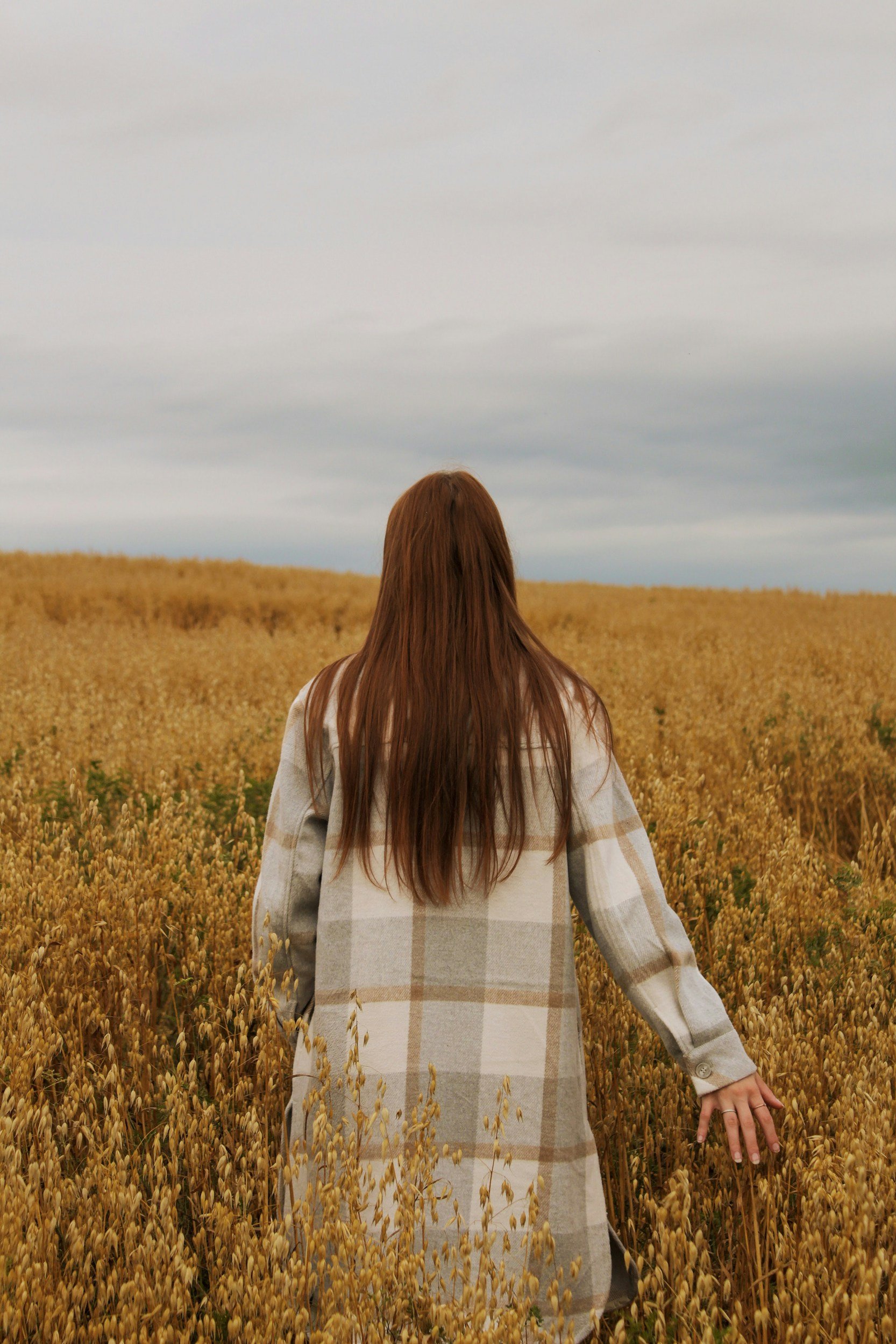 Woman walks through field of flowers in checkered coat