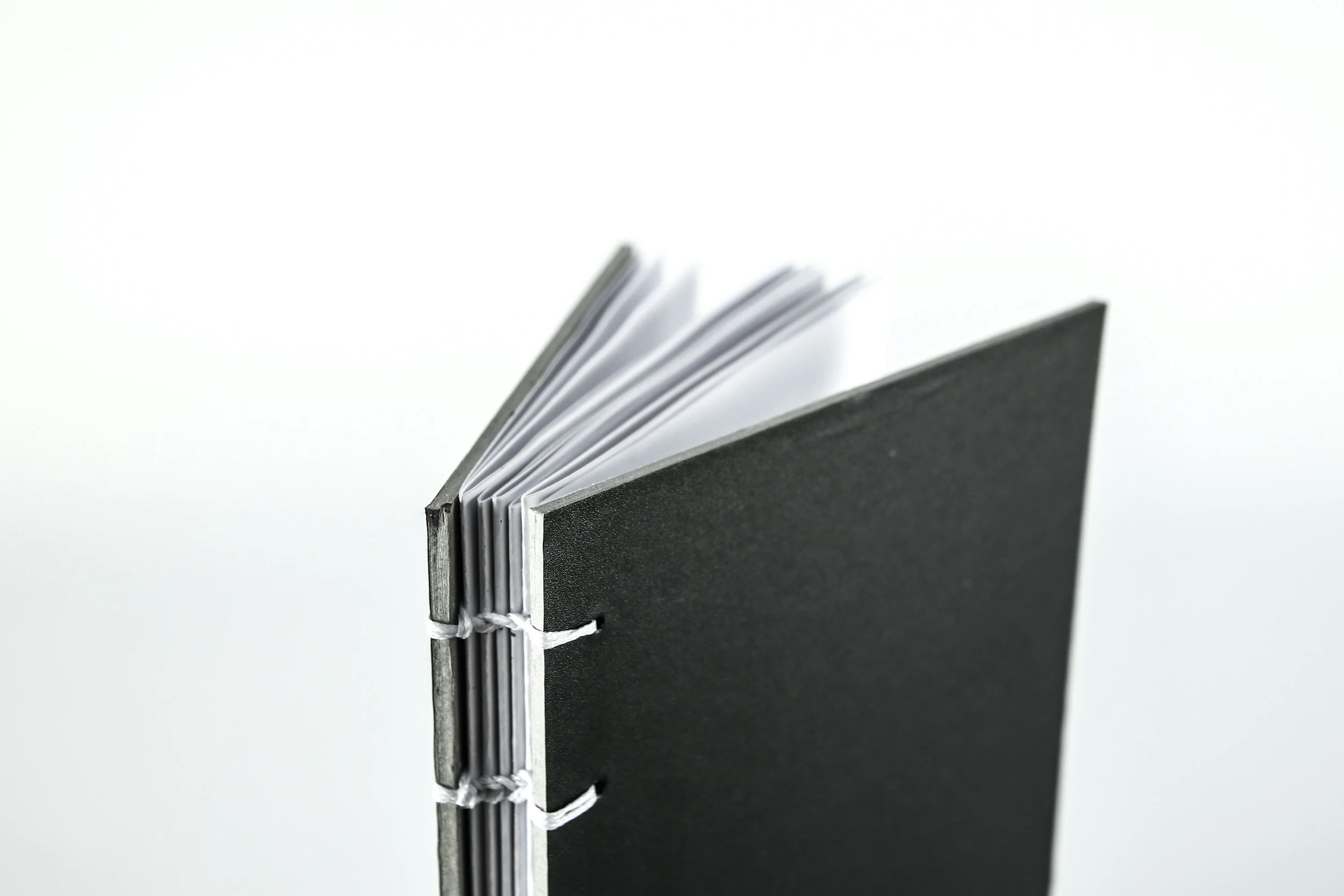Close-up of a black and white spiral-bound notebook with pages fanned out against a white background.