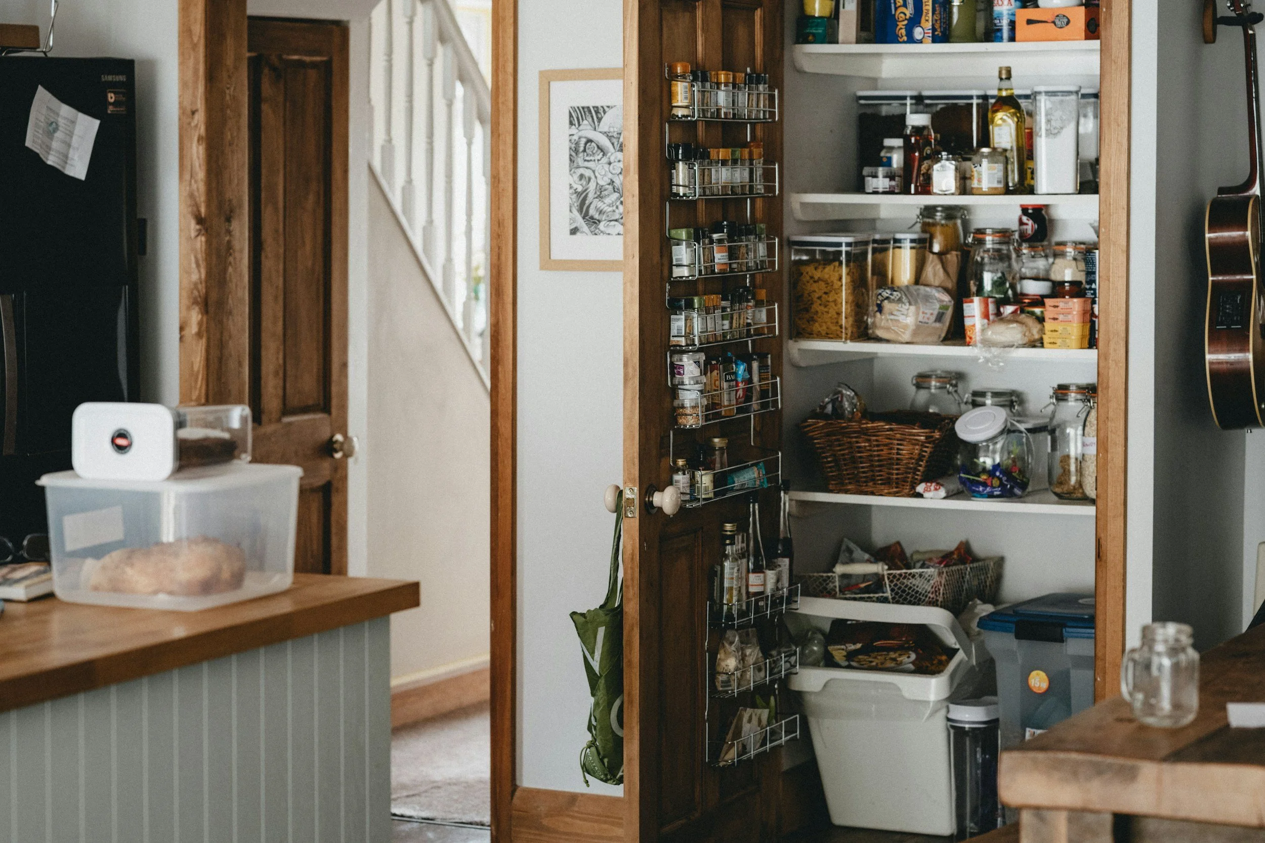 Open pantry filled with jars, canned goods, and spices in a kitchen.