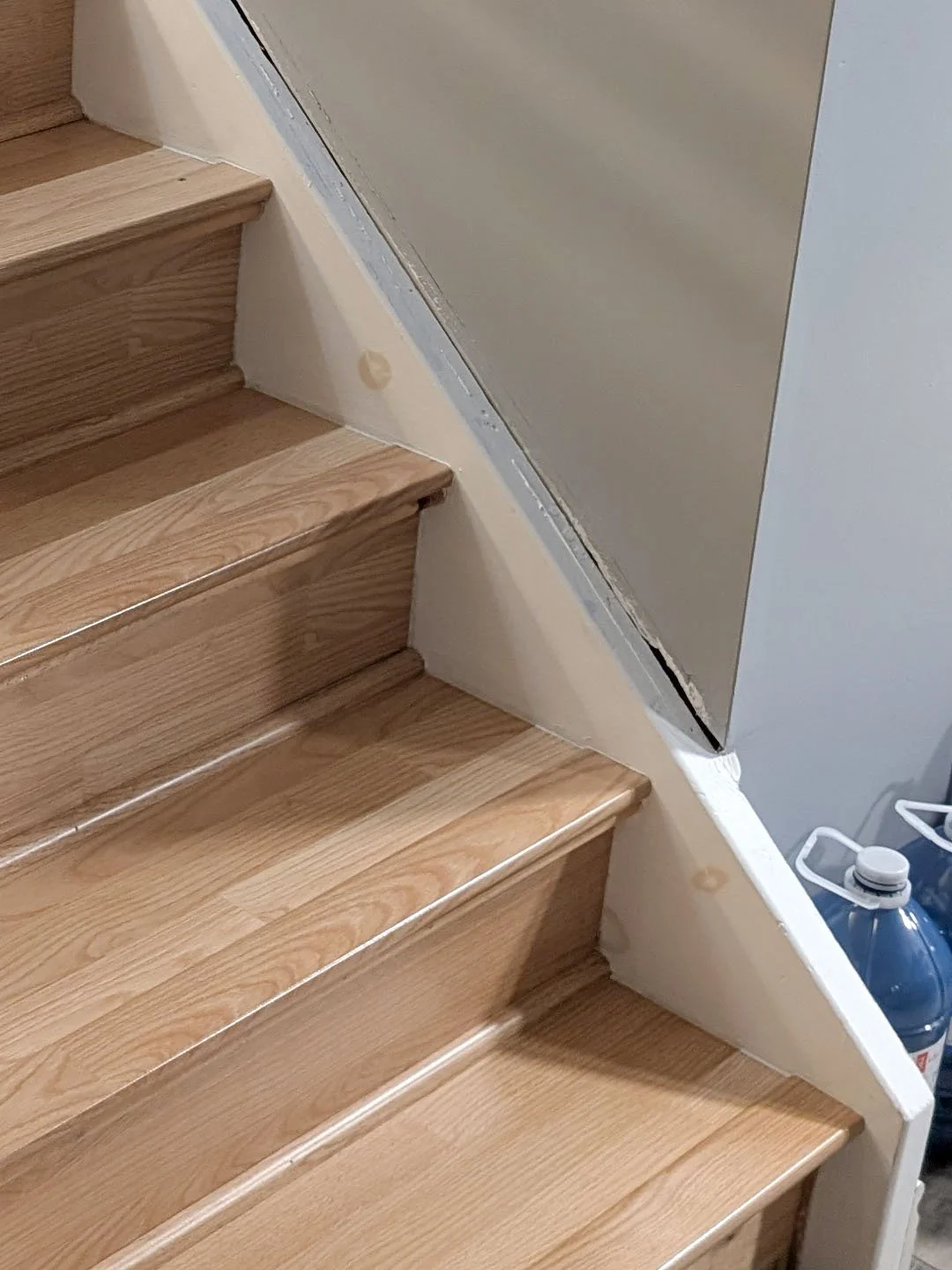 Picture of basement stair before recapping showing laminate flooring and old stringer in Orleans, Ottawa