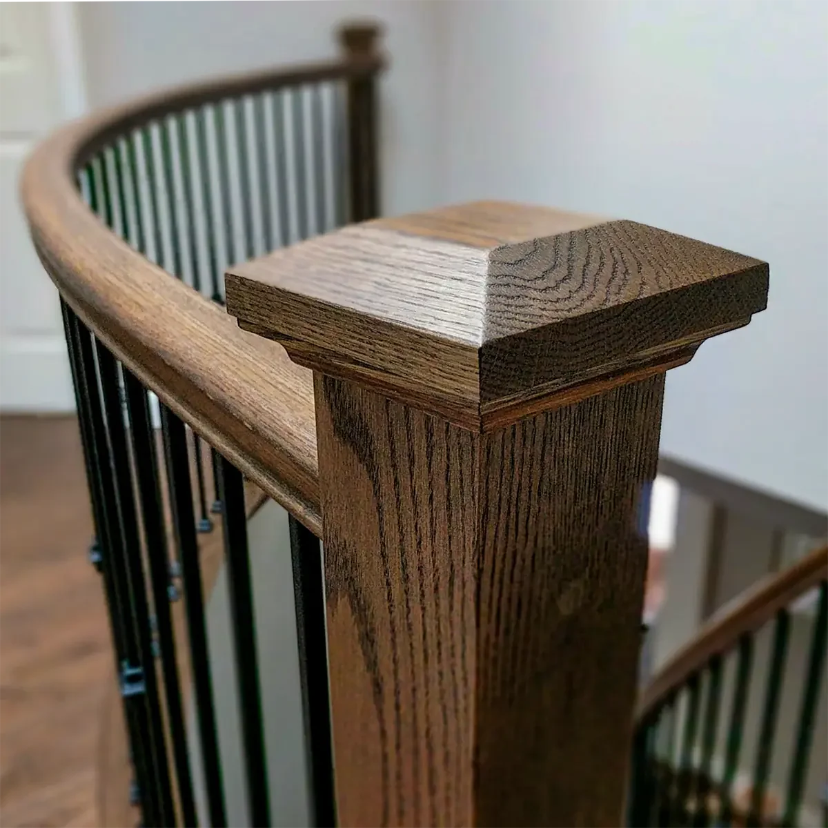 Custom oak curved handrail with oak newel post with contemporary cap and metal spindles in Stittsville, Ottawa.