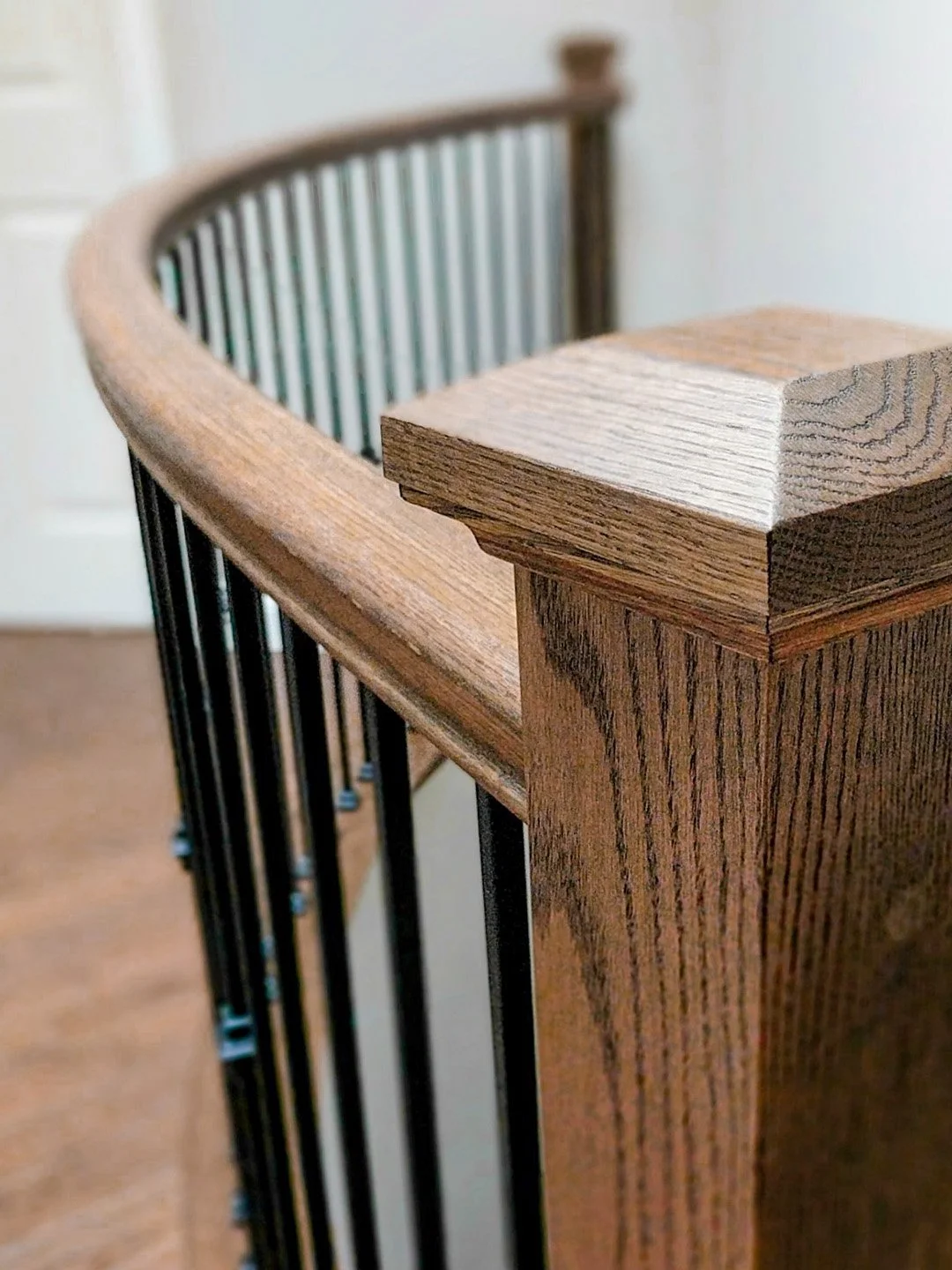 A custom curved oak handrail with metal spindles and square contemporary posts installed by Campbell's Woodcraft in Kanata, Ottawa.