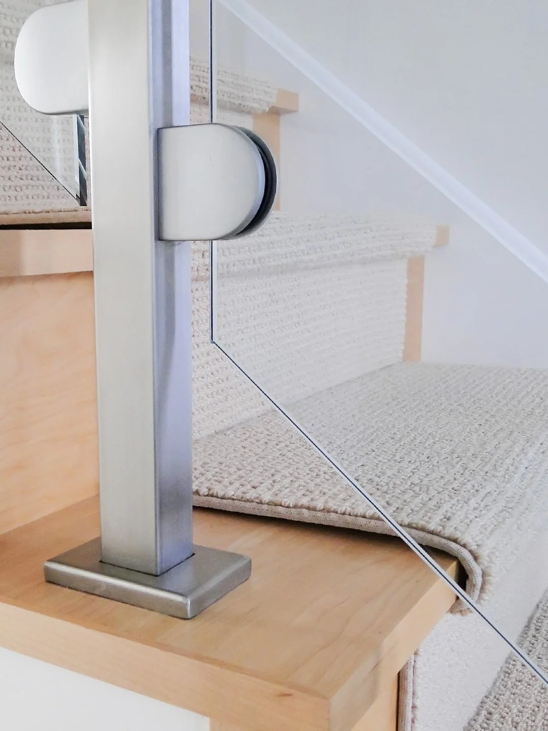 A bespoke stainless steel and glass railing installed on a modern maple staircase installed by Campbell's Woodcraft in a home in Riverside South, Ottawa.