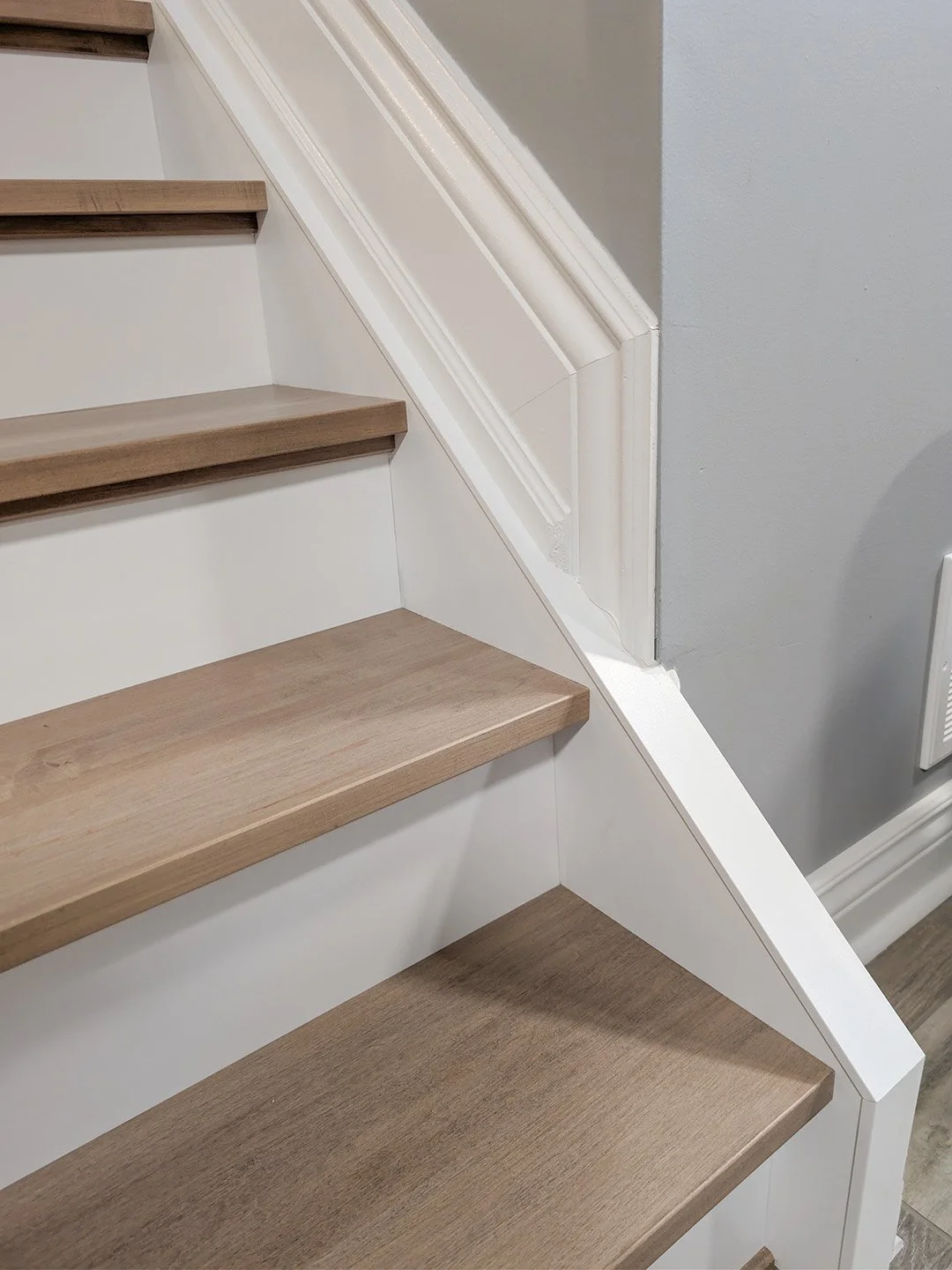 Basement stair recap after shot showing square nosed maple treads with white stringers and risers in home in Orleans, Ottawa.