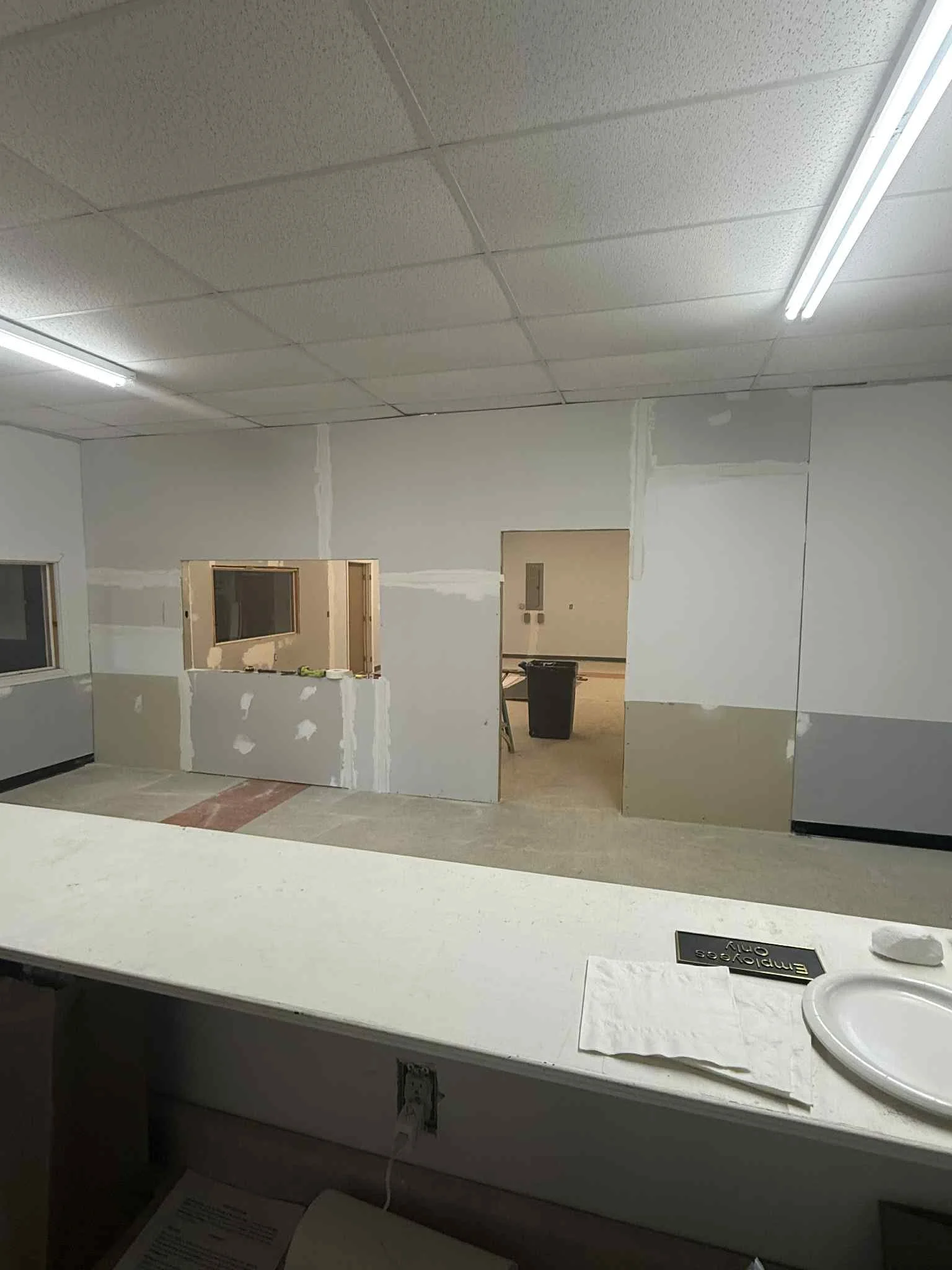 Interior of a building under construction or renovation, with drywall walls being installed and a partially finished opening in the wall.