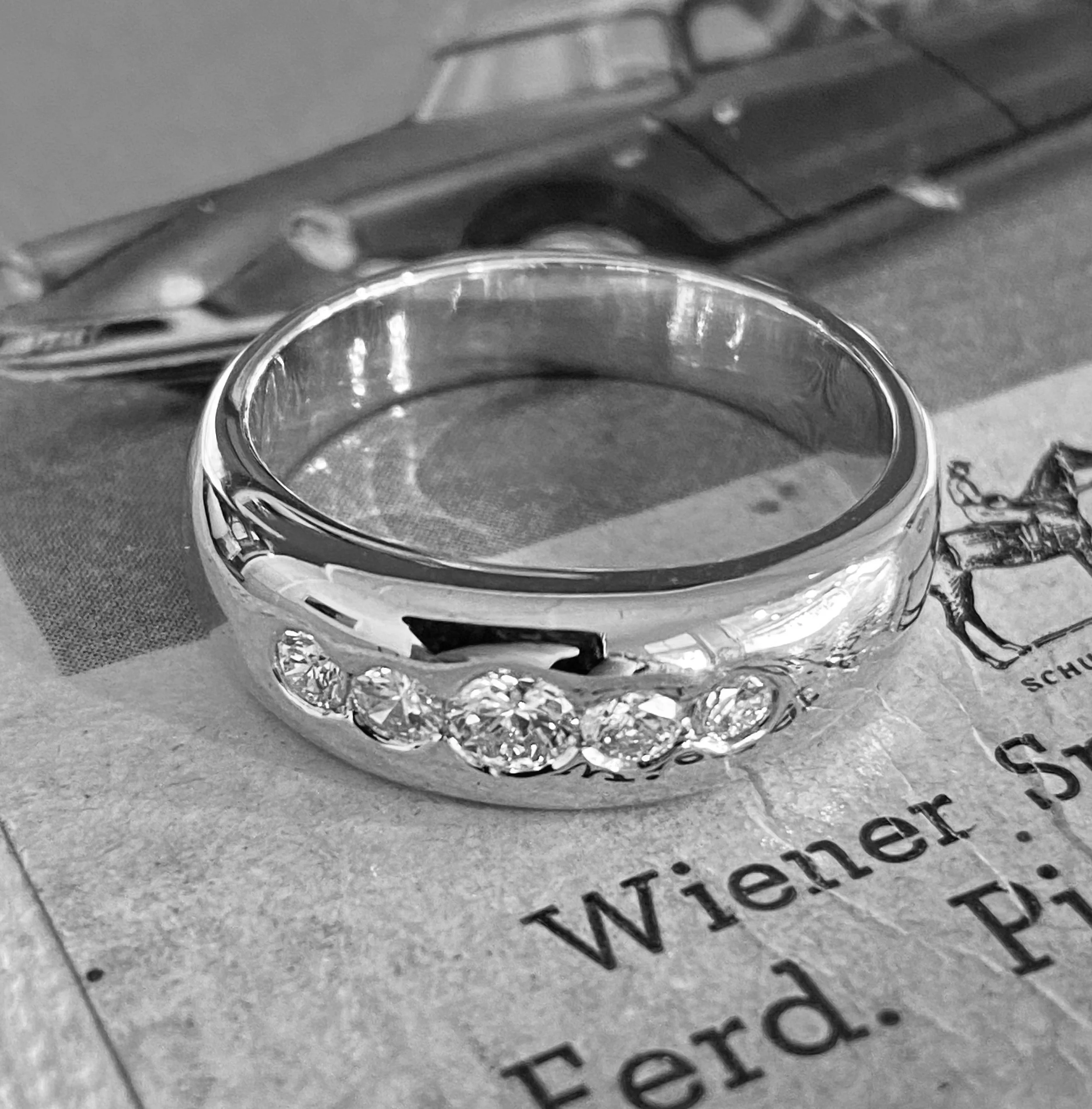 A silver ring with multiple gemstones resting on a newspaper.
