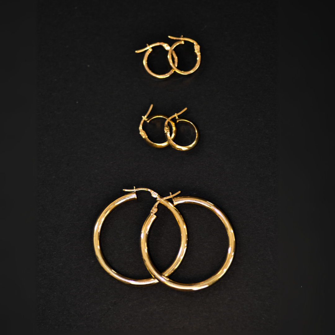 Three pairs of gold hoop earrings on a black background, arranged from smallest to largest.