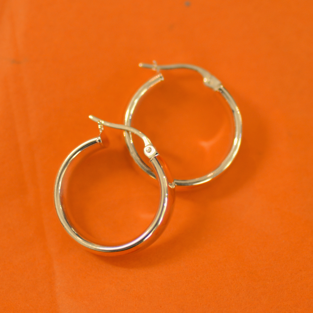 Silver hoop earrings on an orange background.
