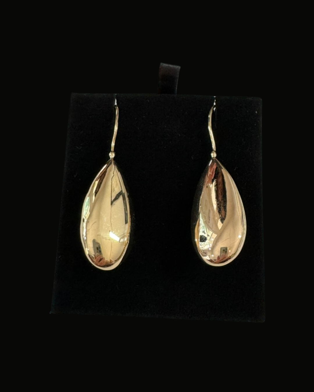 Gold teardrop-shaped dangle earrings on black display