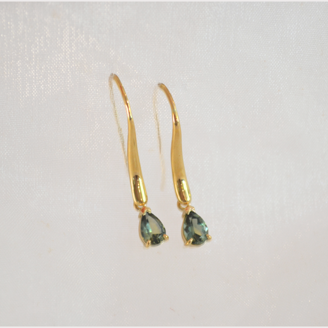 Gold earrings with teardrop-shaped dark green gemstones.