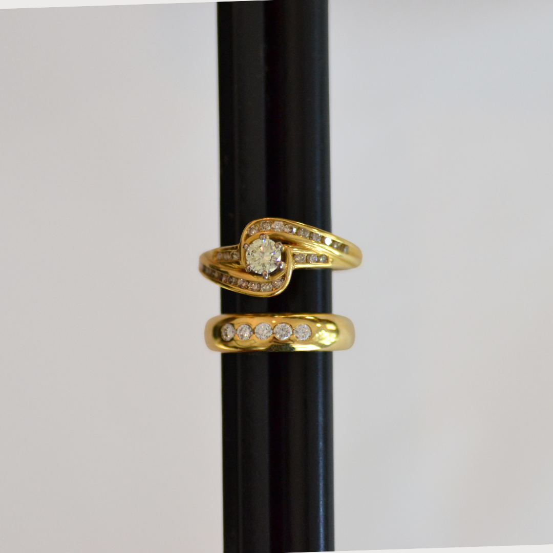 Two gold rings with diamonds on a black ring holder.
