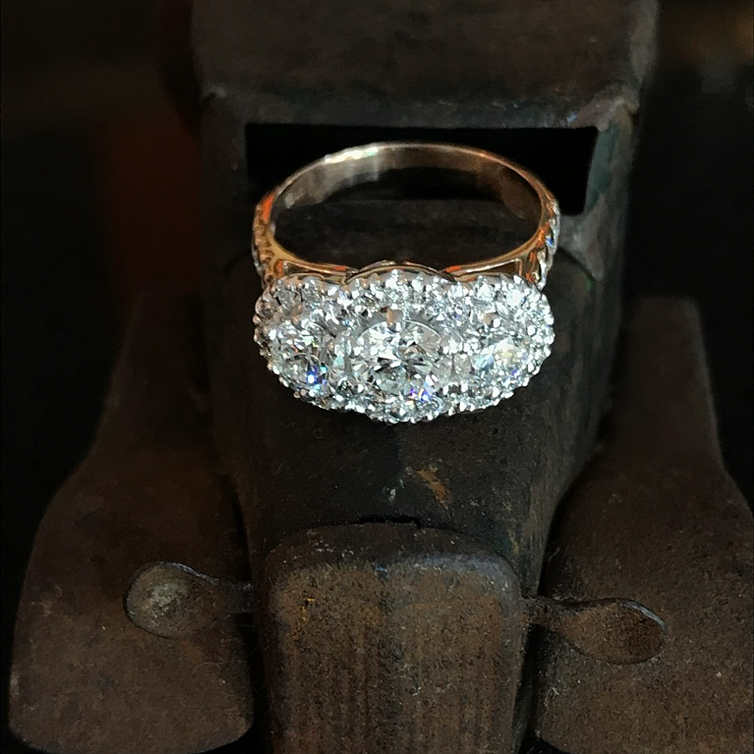 A silver ring adorned with multiple sparkling diamonds, placed on a rusty metal surface.
