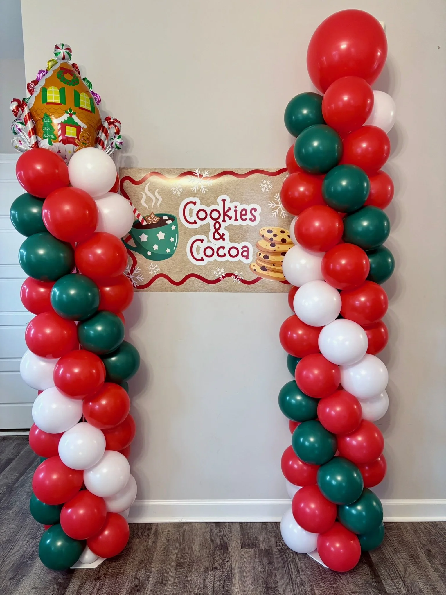 Christmas balloon arch in red, green, and white with Cookies and Cocoa sign