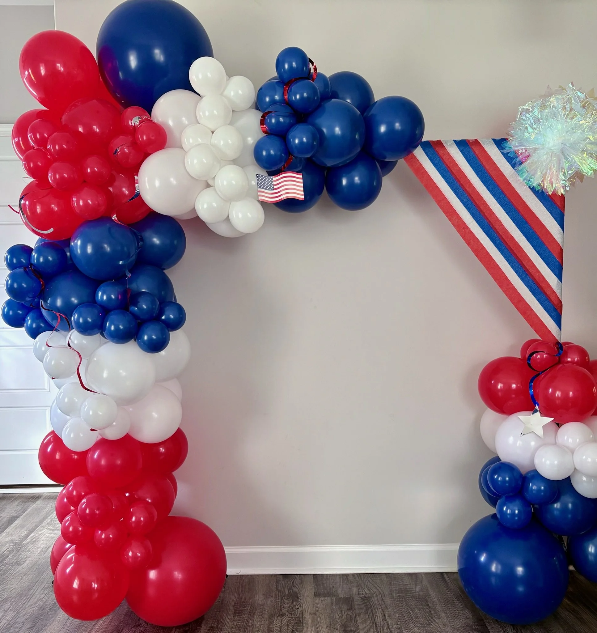Red, white, and blue patriotic balloon arch with star accents
