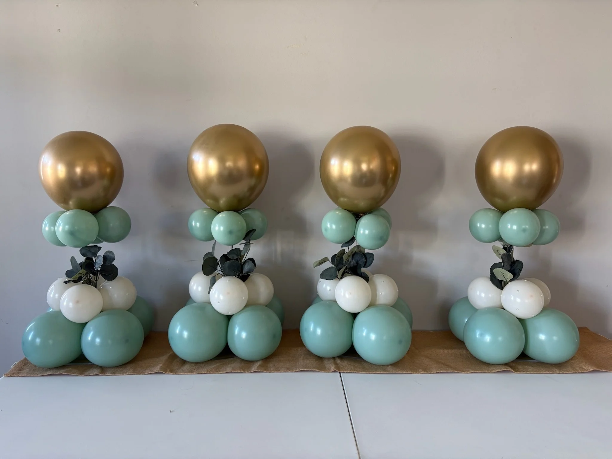 Elegant balloon columns with gold, sage green, and white balloons