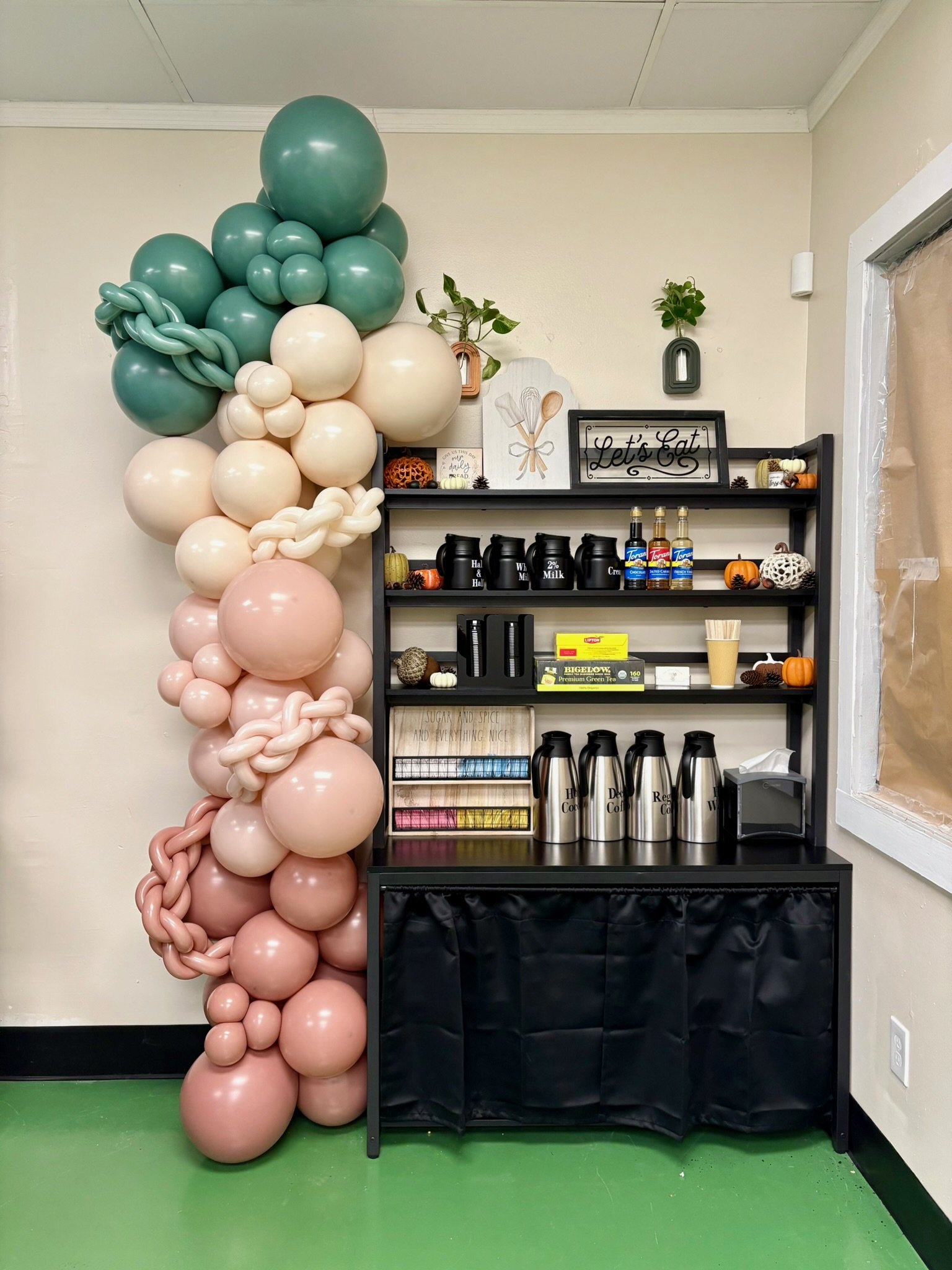 Organic balloon column in blush, cream, and teal next to a coffee station