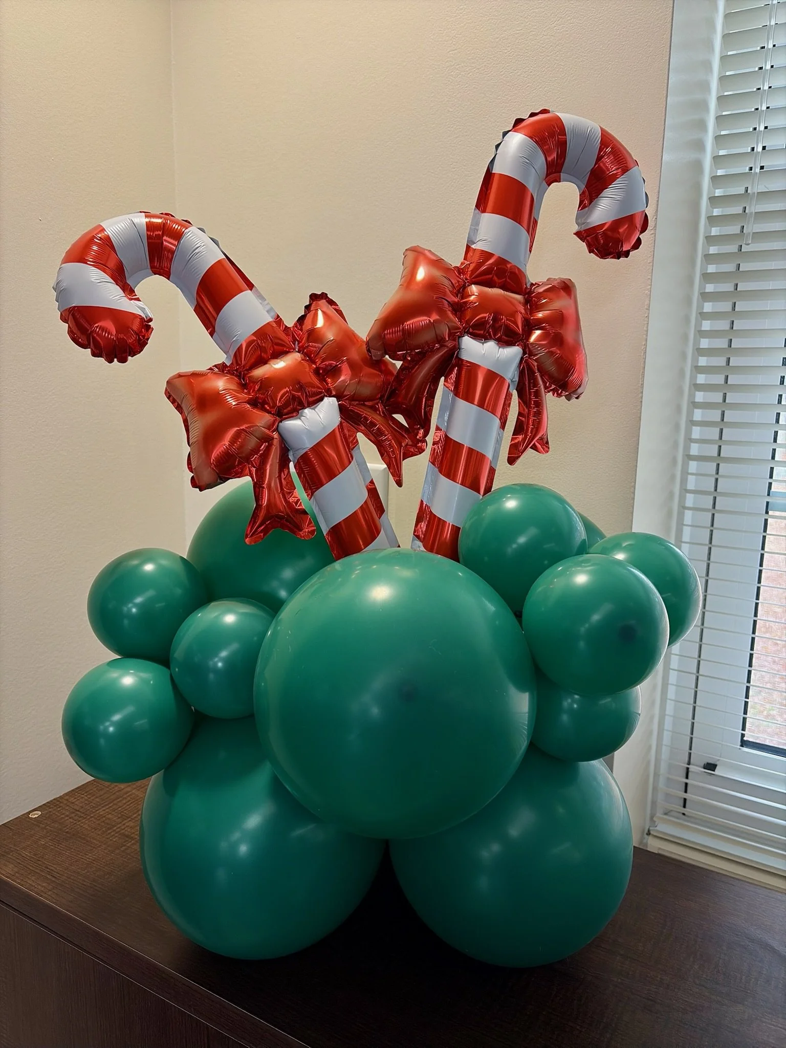 Christmas balloon centerpiece with candy cane foil balloons and red bows