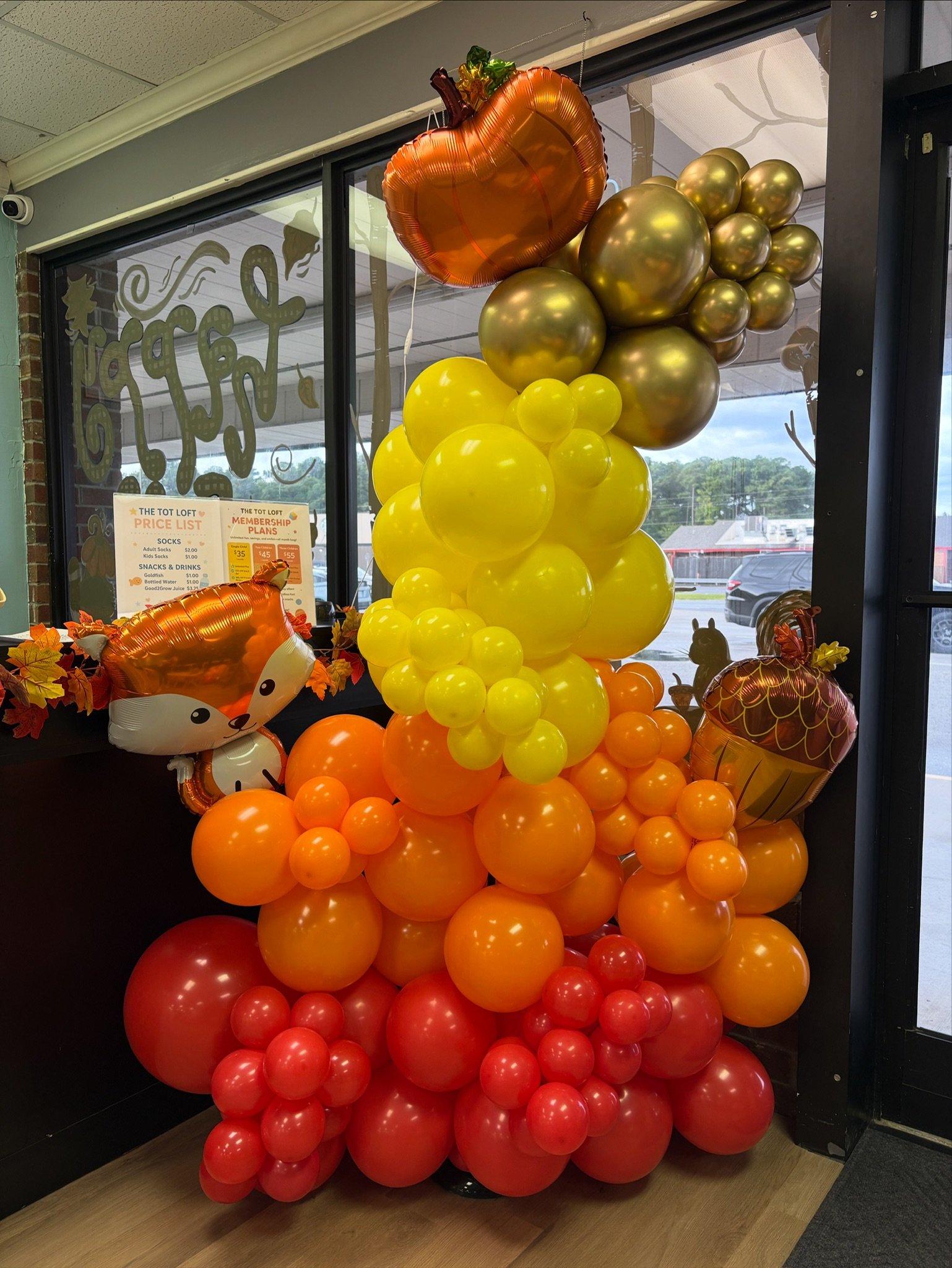 Fall balloon display in orange, yellow, and red outside a storefront window