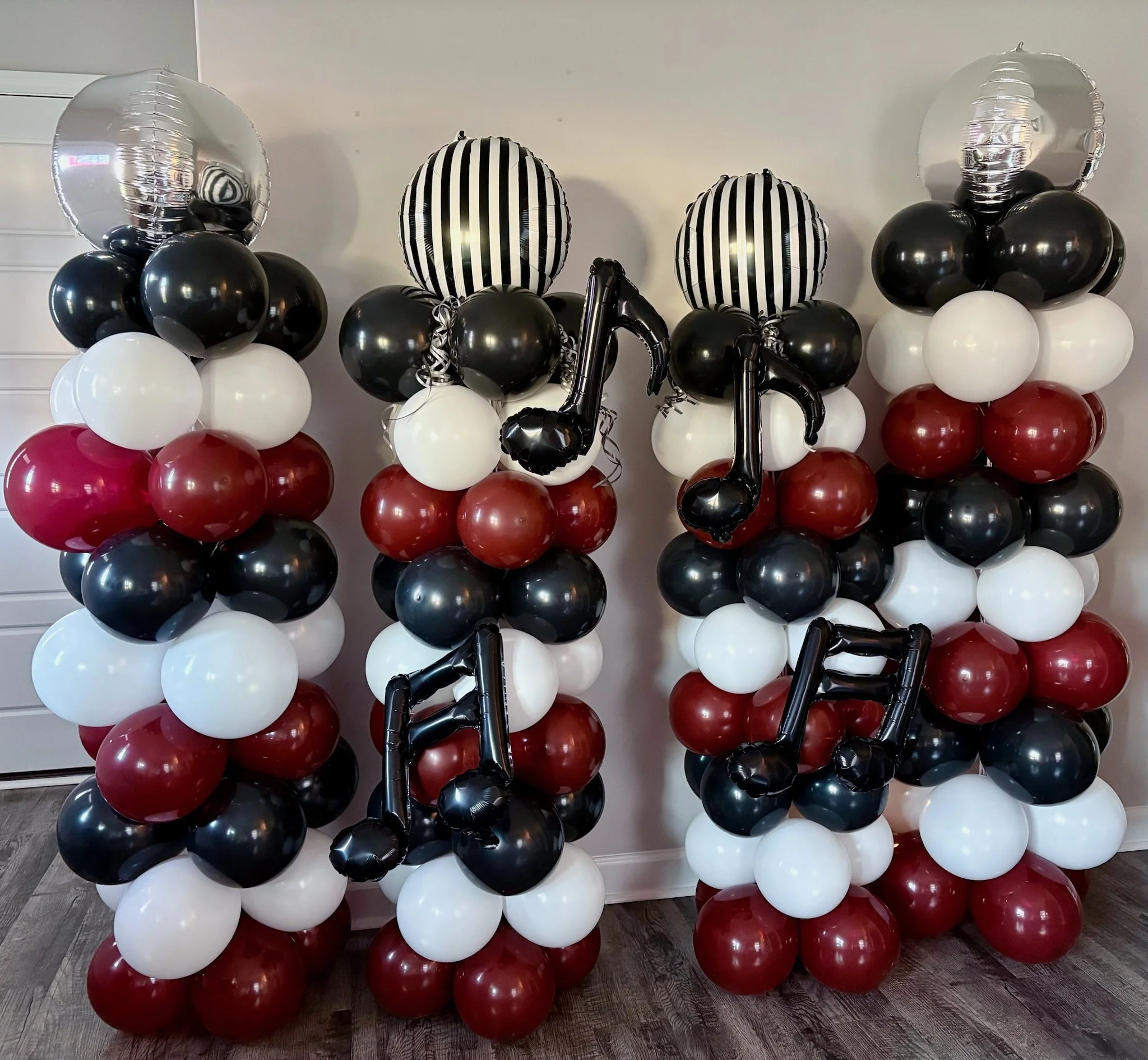Black, white, and burgundy balloon columns with disco ball toppers