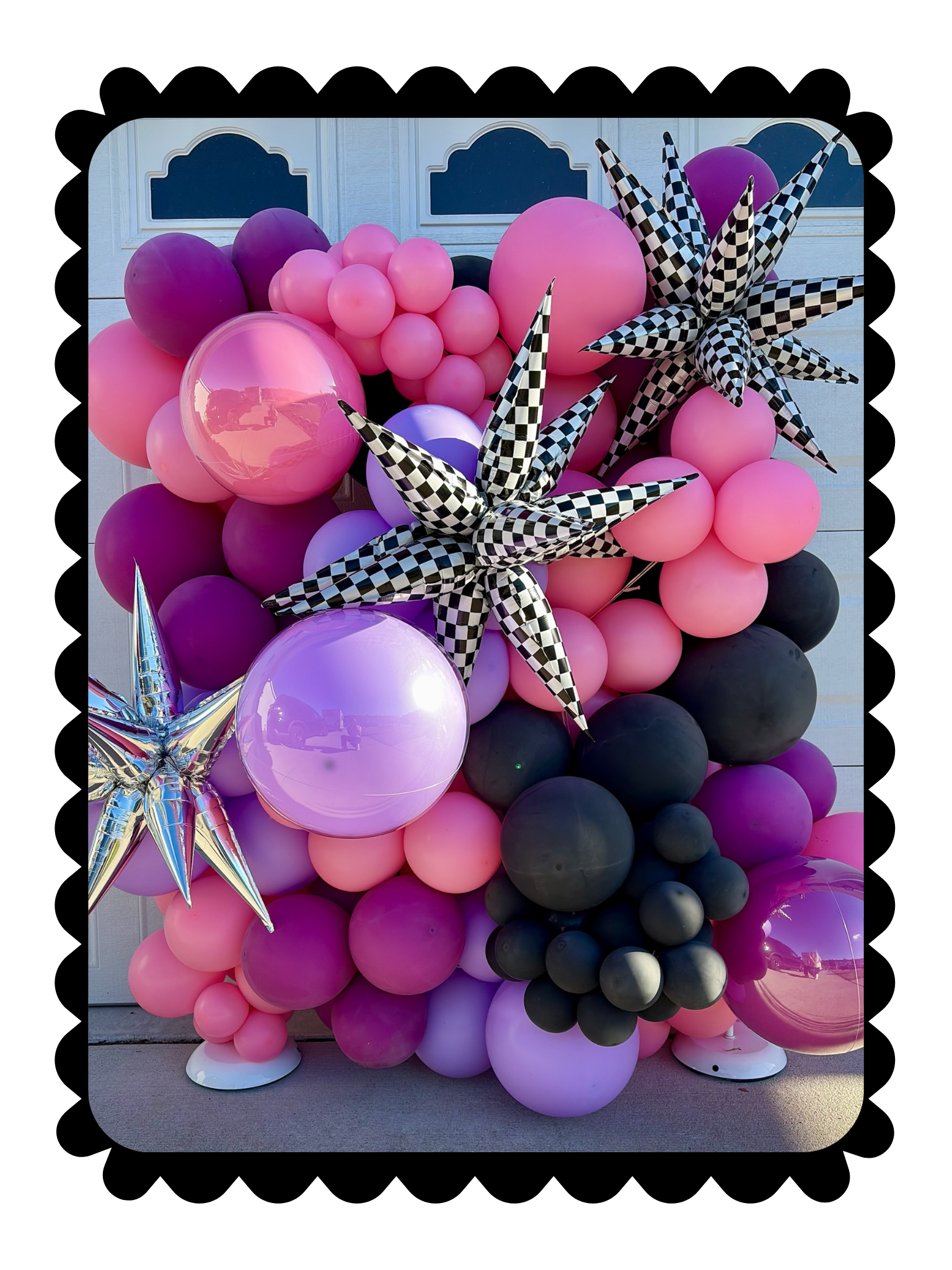 Pink, purple, and black balloon arrangement with metallic star accents and checkered star balloons for a bold event backdrop.