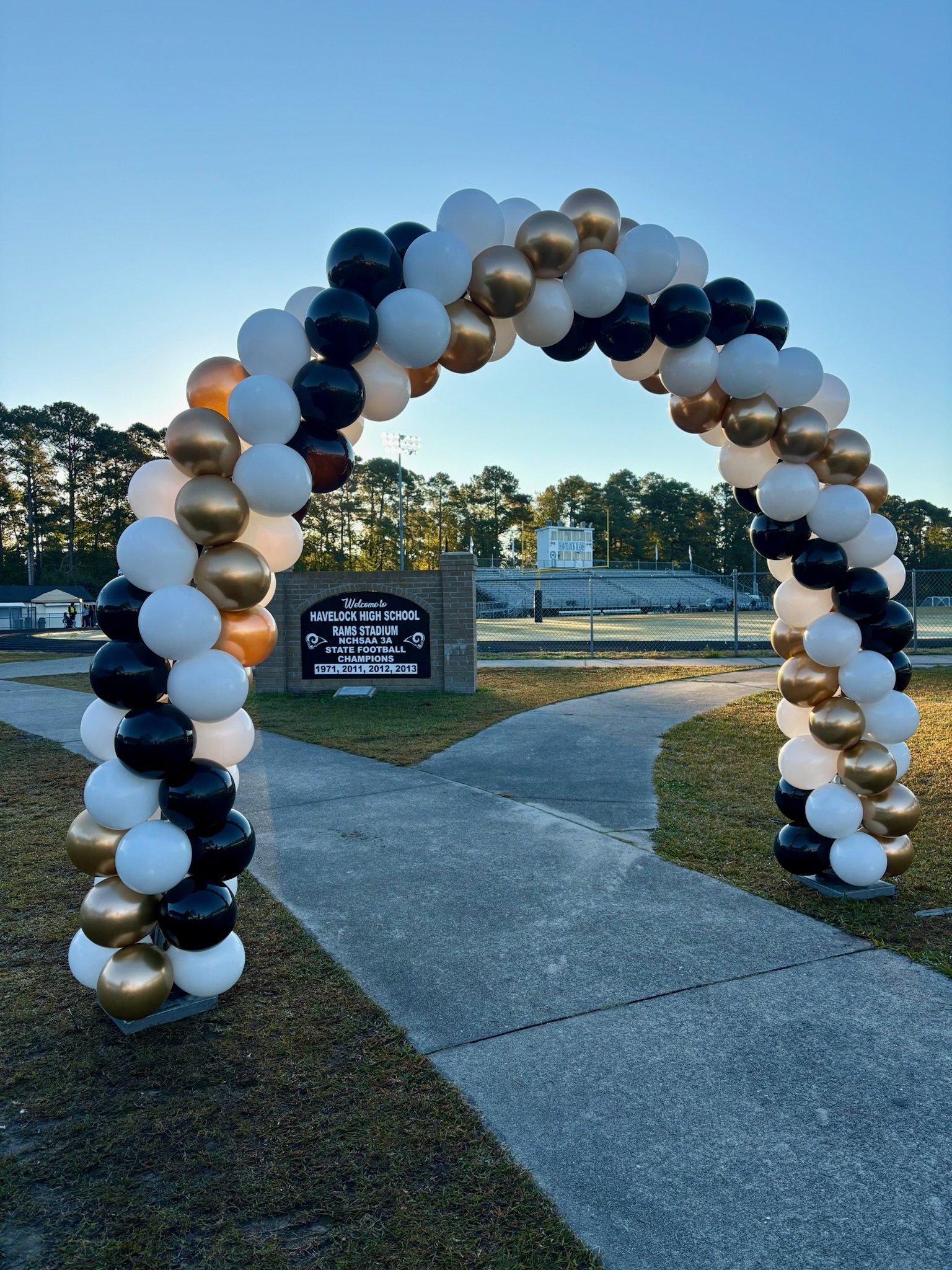 Outdoor balloon arch in navy, white, and gold for an event entrance