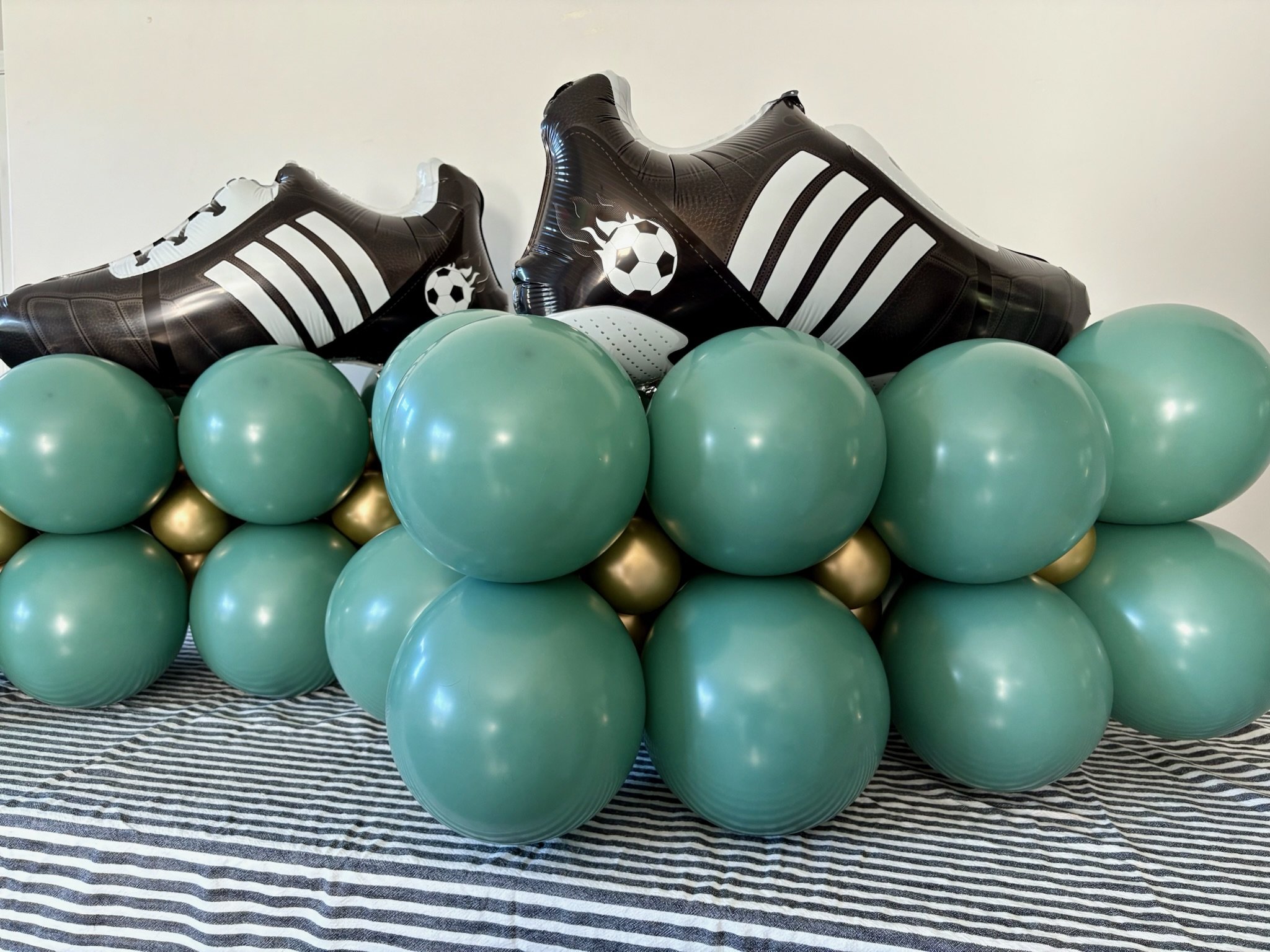 Soccer-themed balloon garland with green balloons and black-and-white soccer ball accents