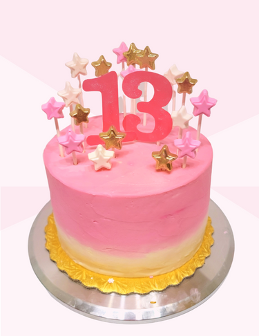 A pink and yellow birthday cake with stars and a large red number 13 on top, decorated with star-shaped candles.