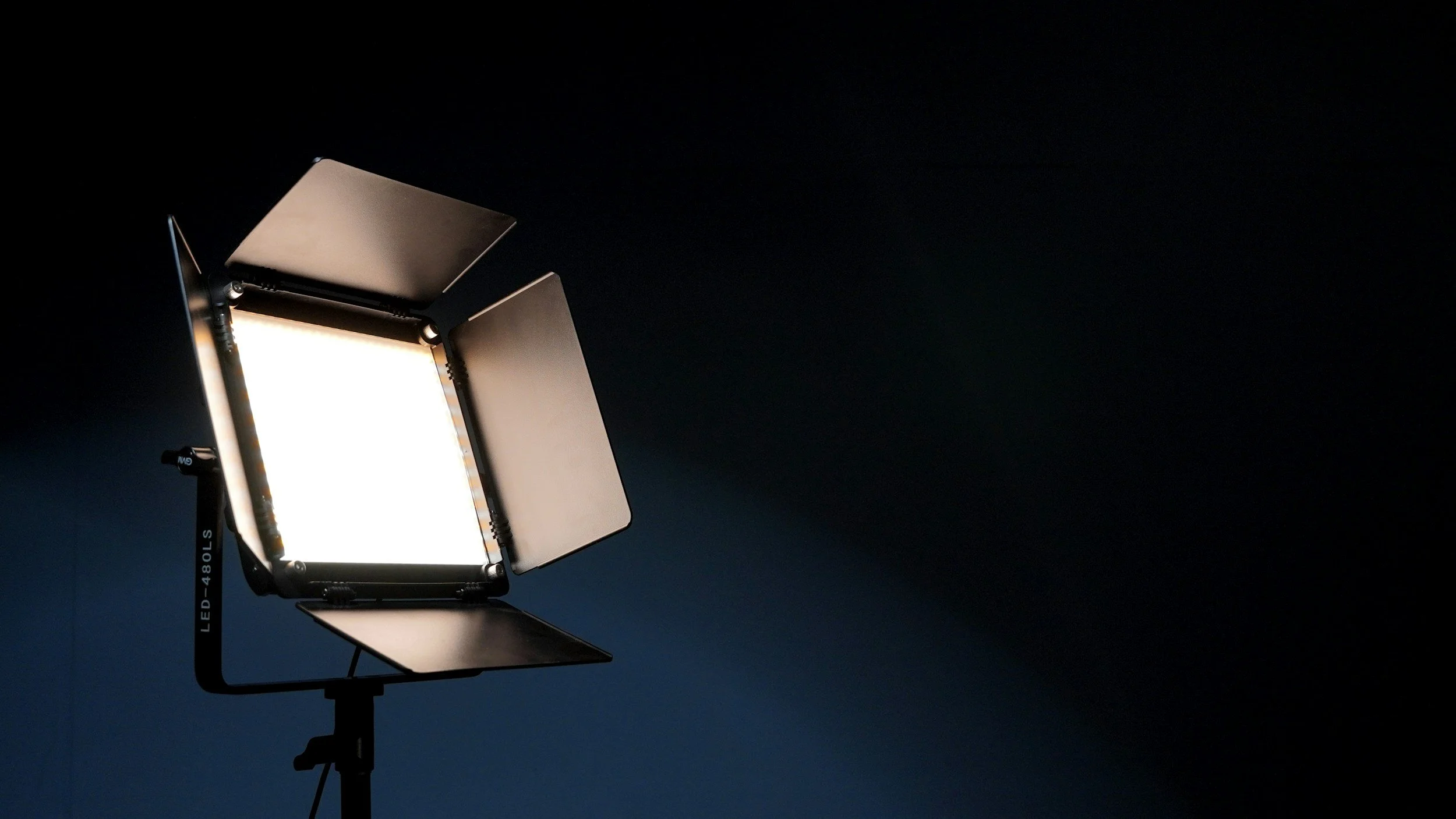 Studio softbox light on a stand against a dark background.