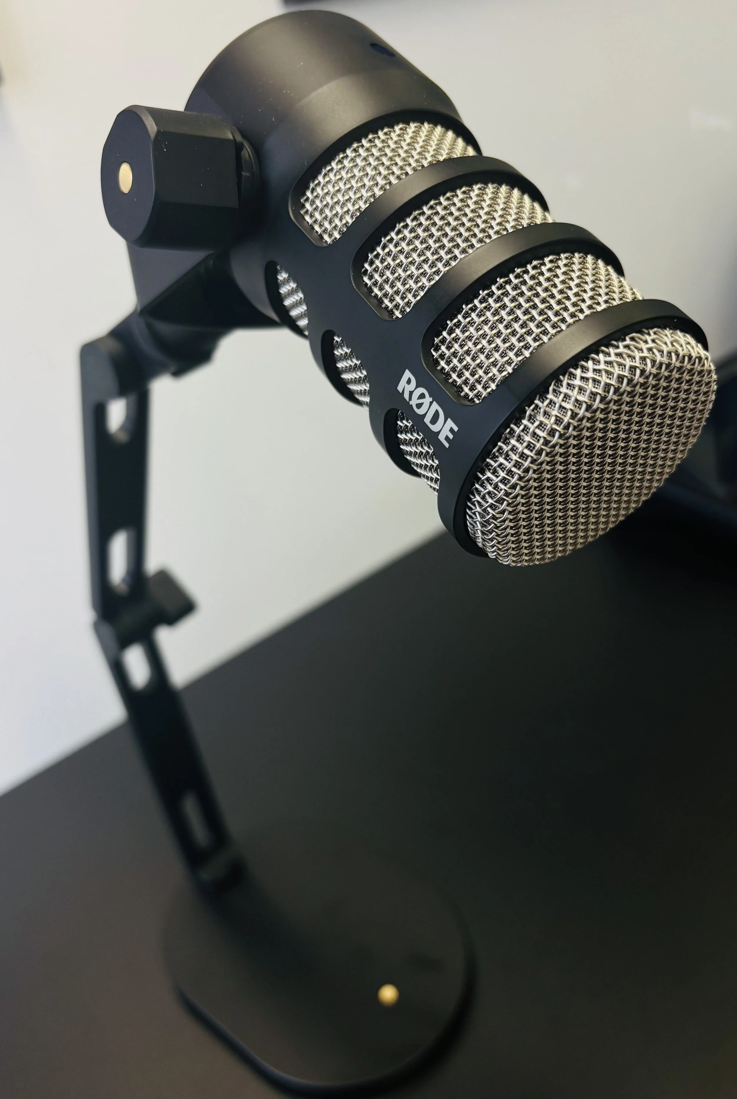 Close-up image of a Rode microphone mounted on a black stand against a plain background.