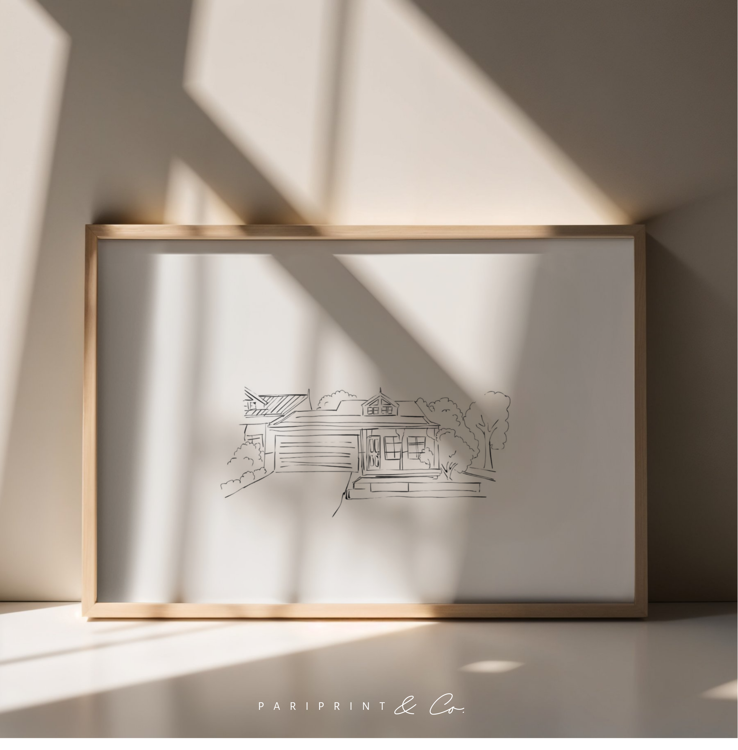 Framed line drawing of a house with trees, set on a white surface with shadows cast across the frame.