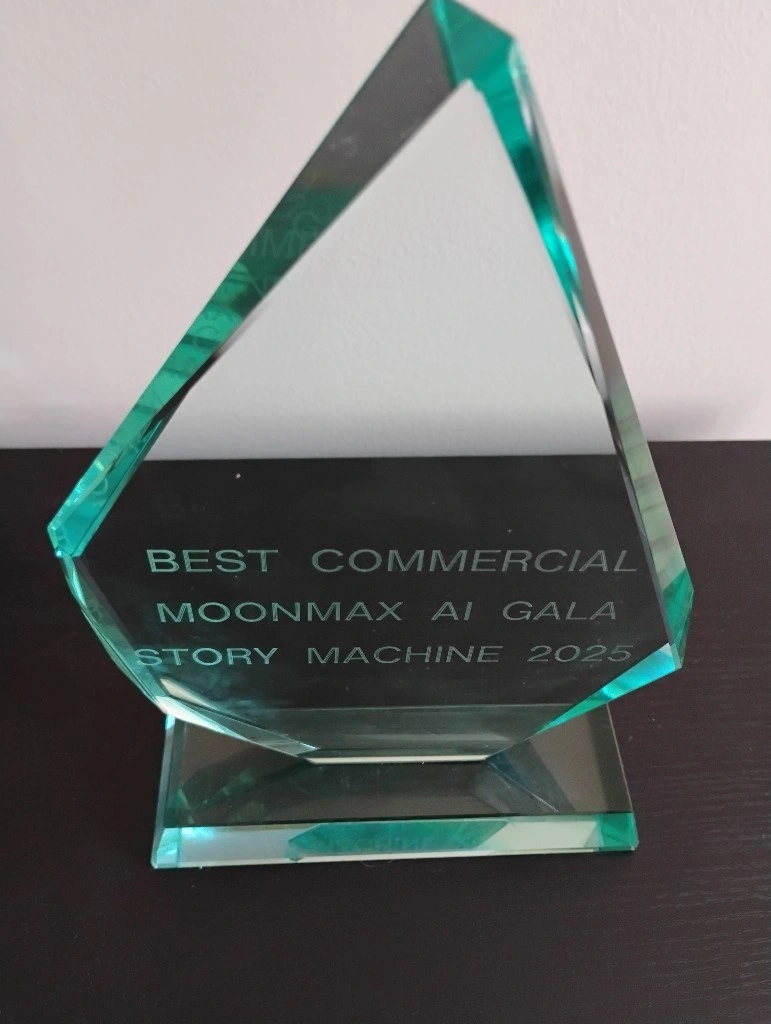 A glass award with an angular design, inscribed with "Best Commercial Moonmax AI Gala Story Machine 2025."