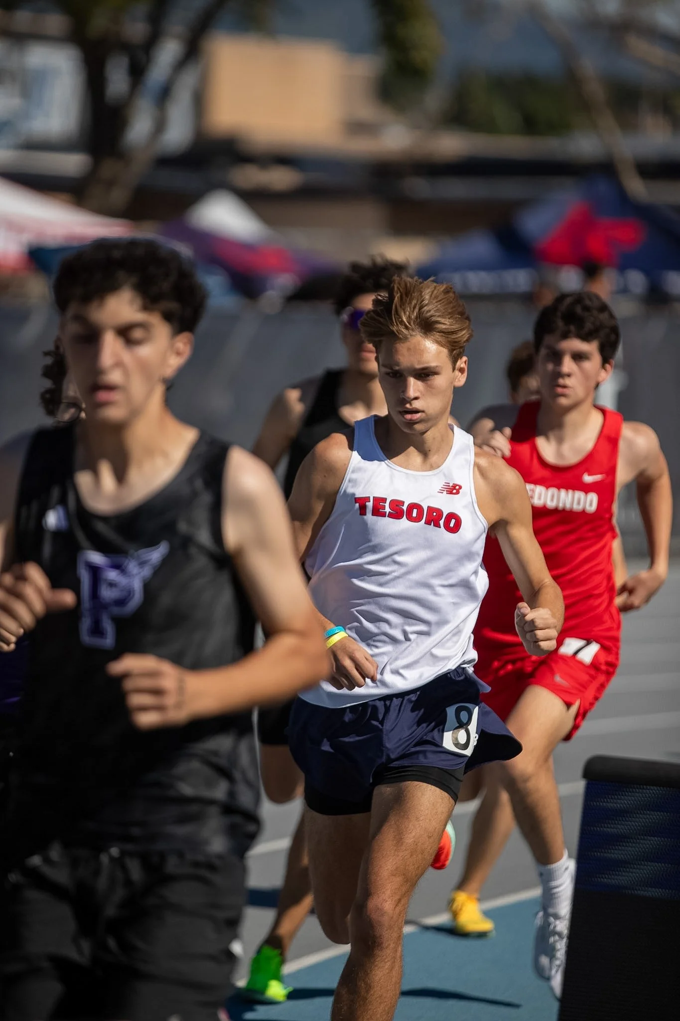 Photography of young male runners competing in a track race outdoors by photographer Leo Assalian.