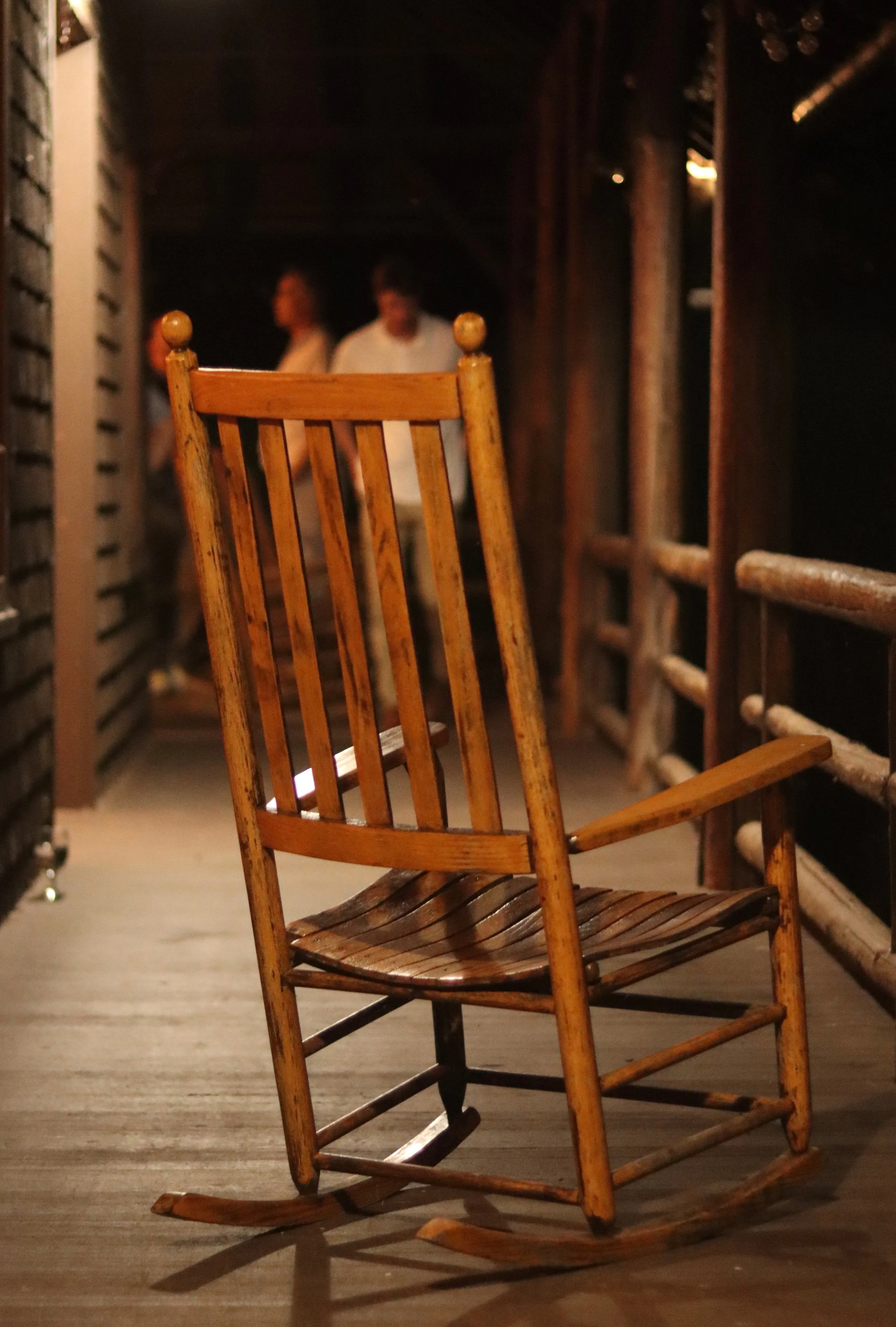 Photography of a wooden rocking chair on a porch at night, by photographer Leo Assalian.