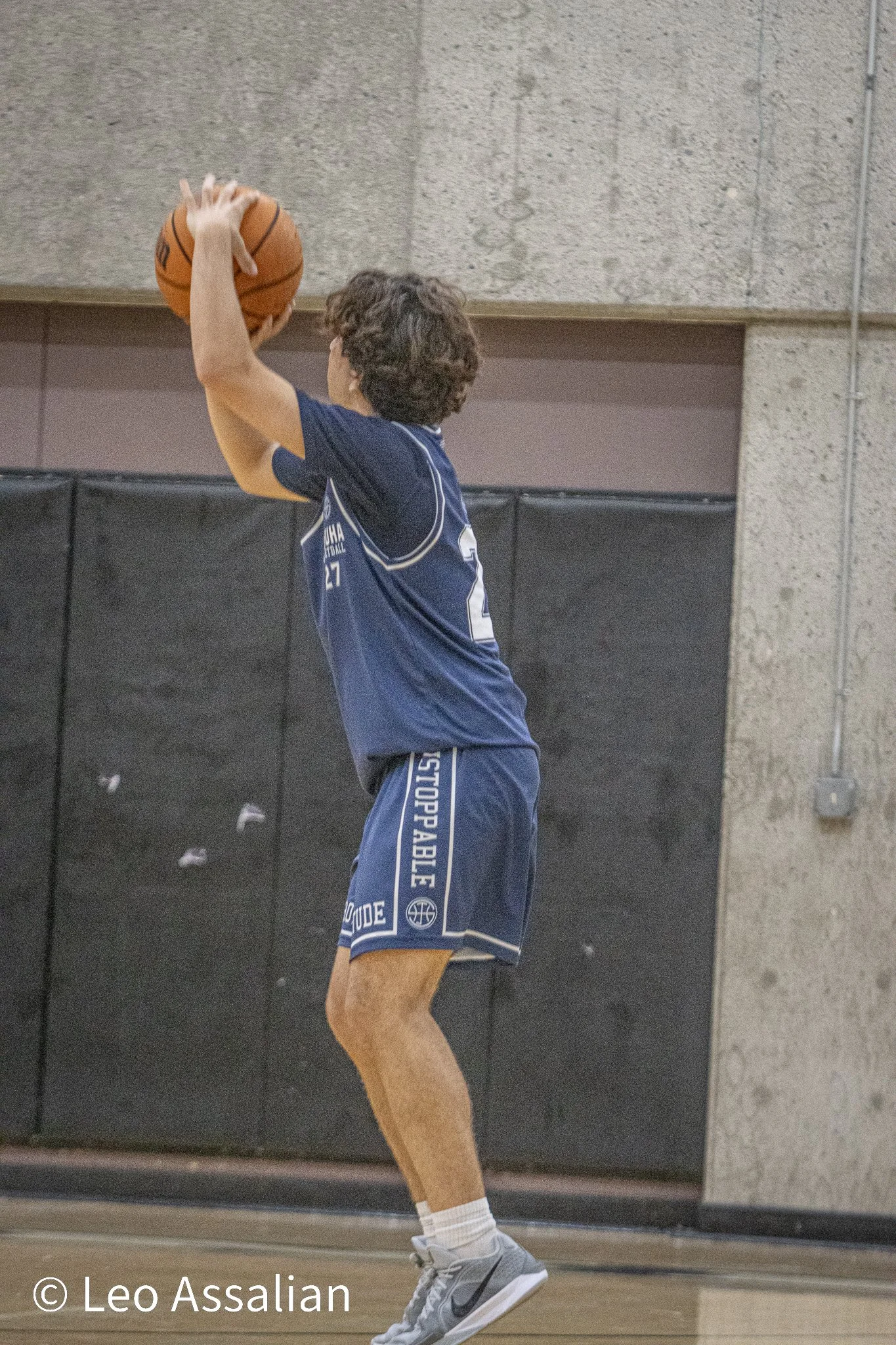 A man in a blue basketball uniform preparing to shoot a basketball in an indoor gym.
