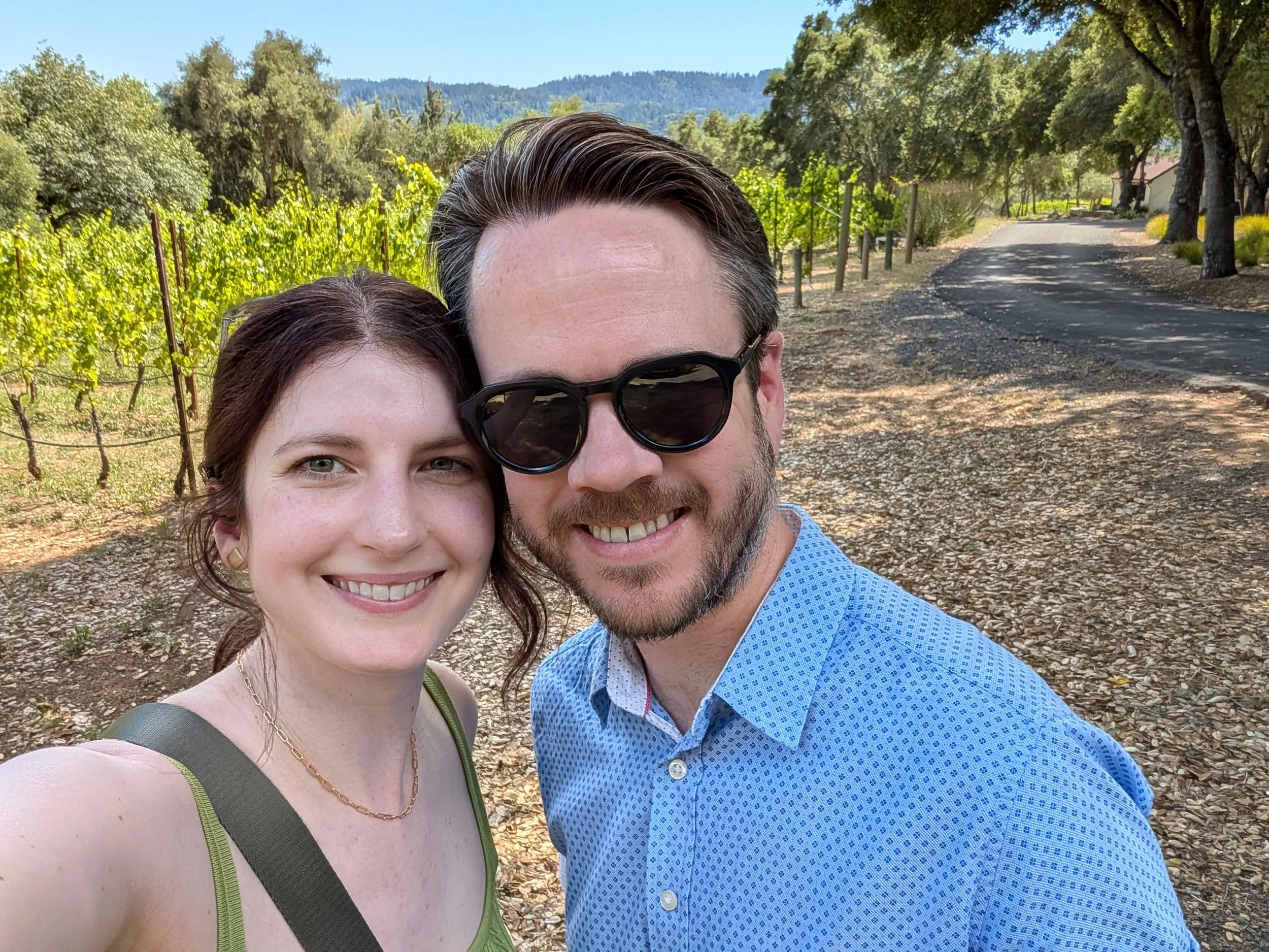 A man and woman smiling in front of a vineyard at Reeve Wines in Healdsburg, California