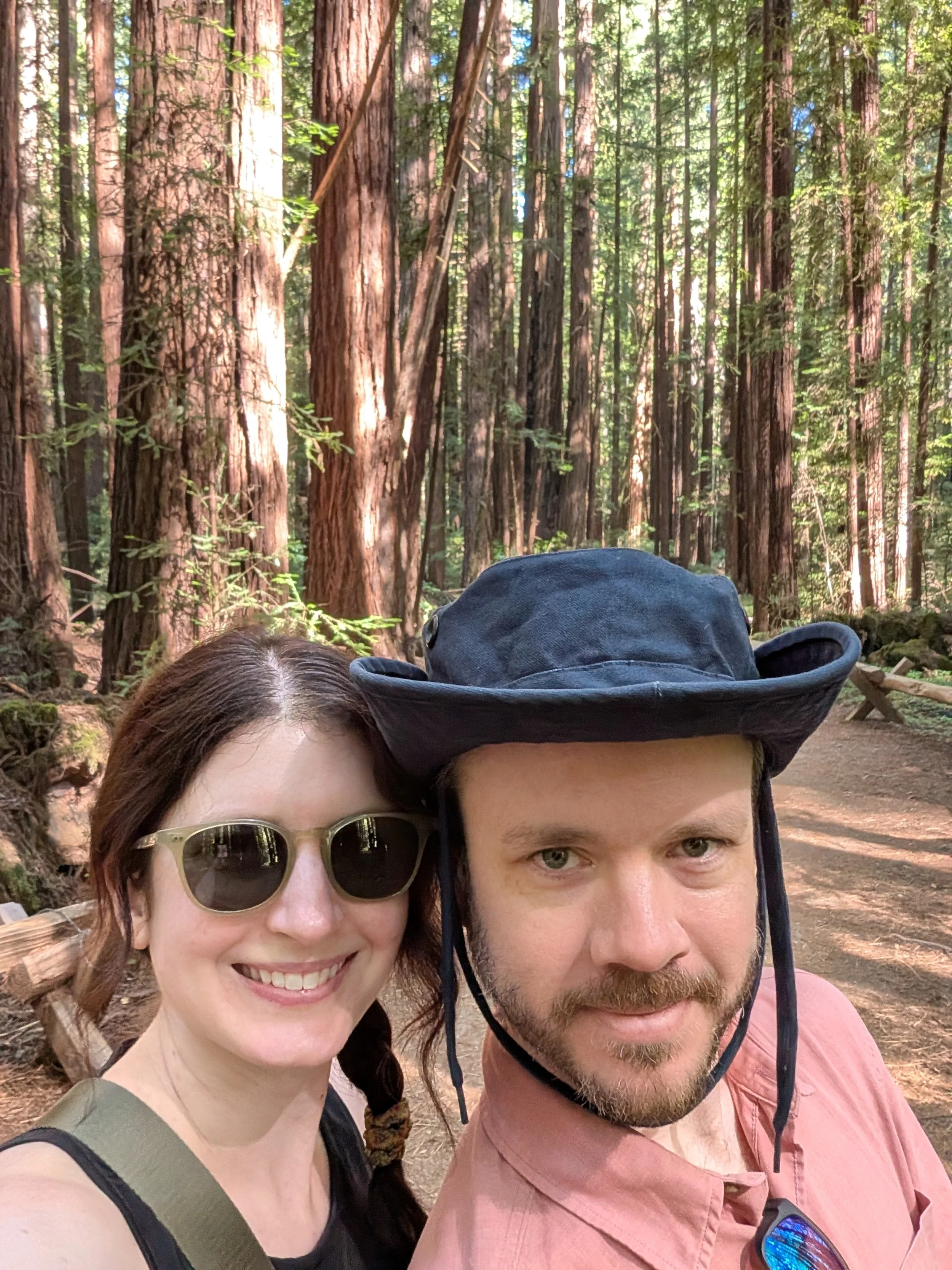 A man and a woman smiling in front of redwood trees at Armstrong Woods