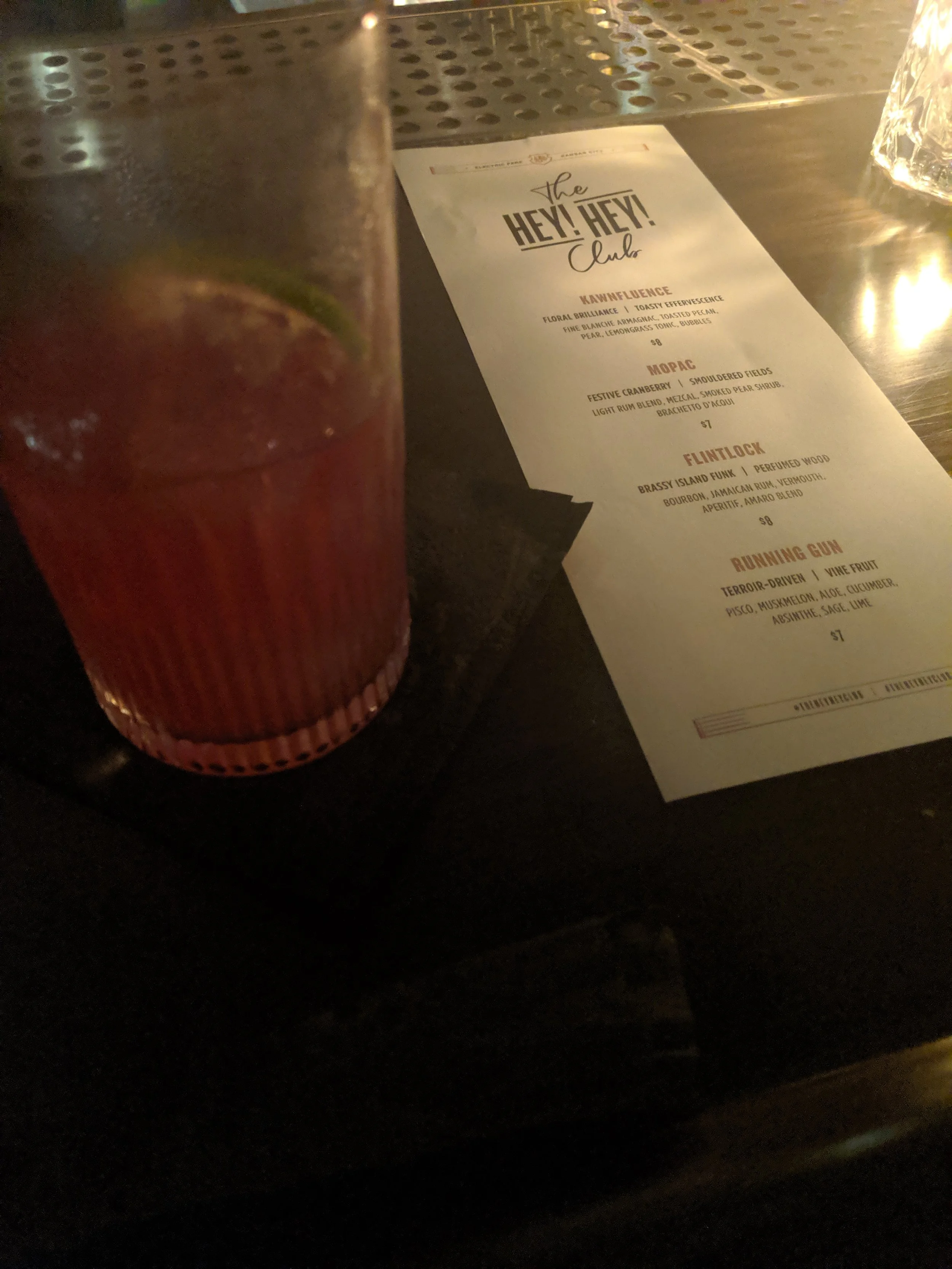 A cocktail and menu on a bar at Hey Hey Club in Kanas City