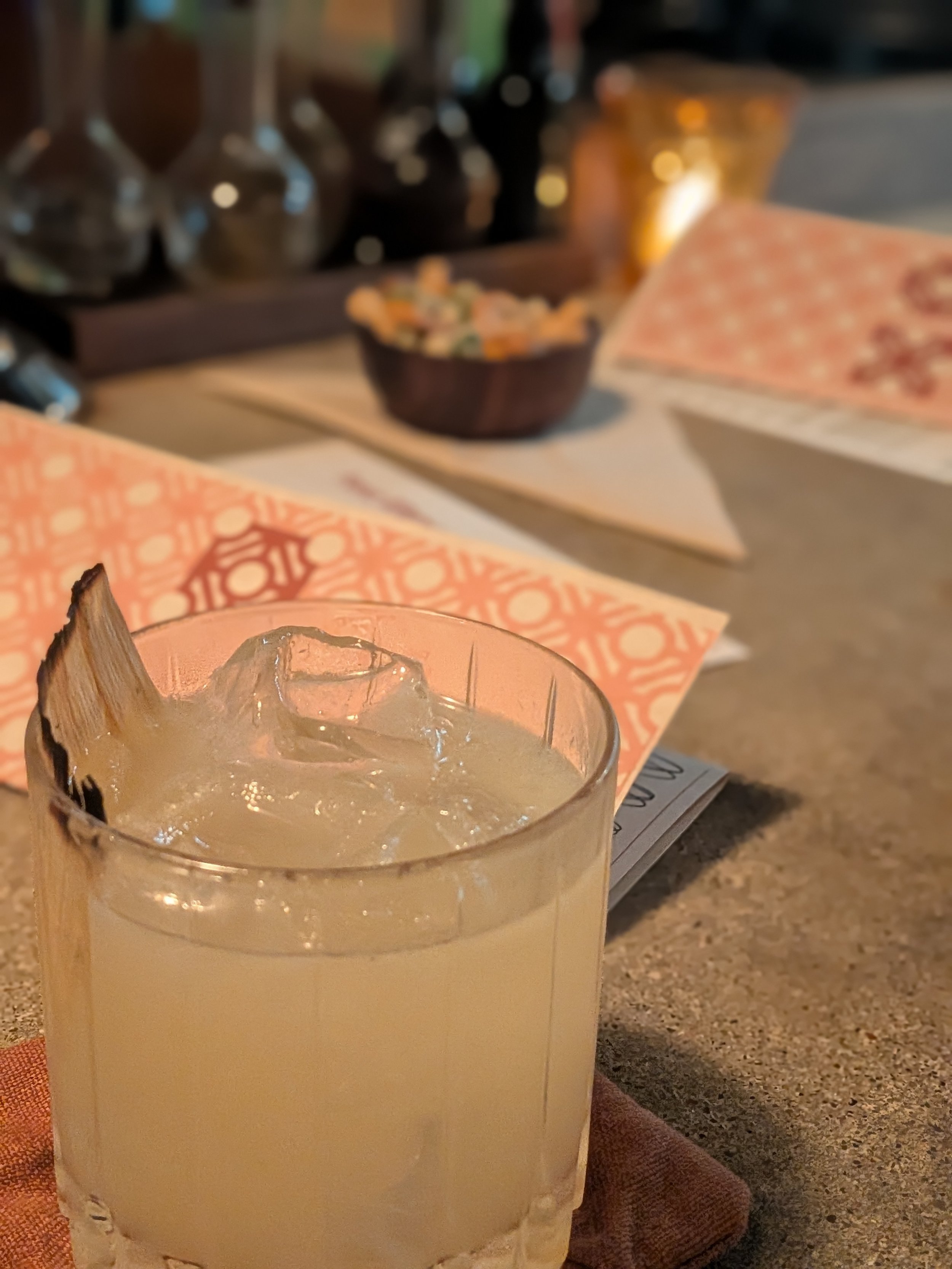 A cocktail with menus and bar snacks in the background at XO Hifi in Kansas City