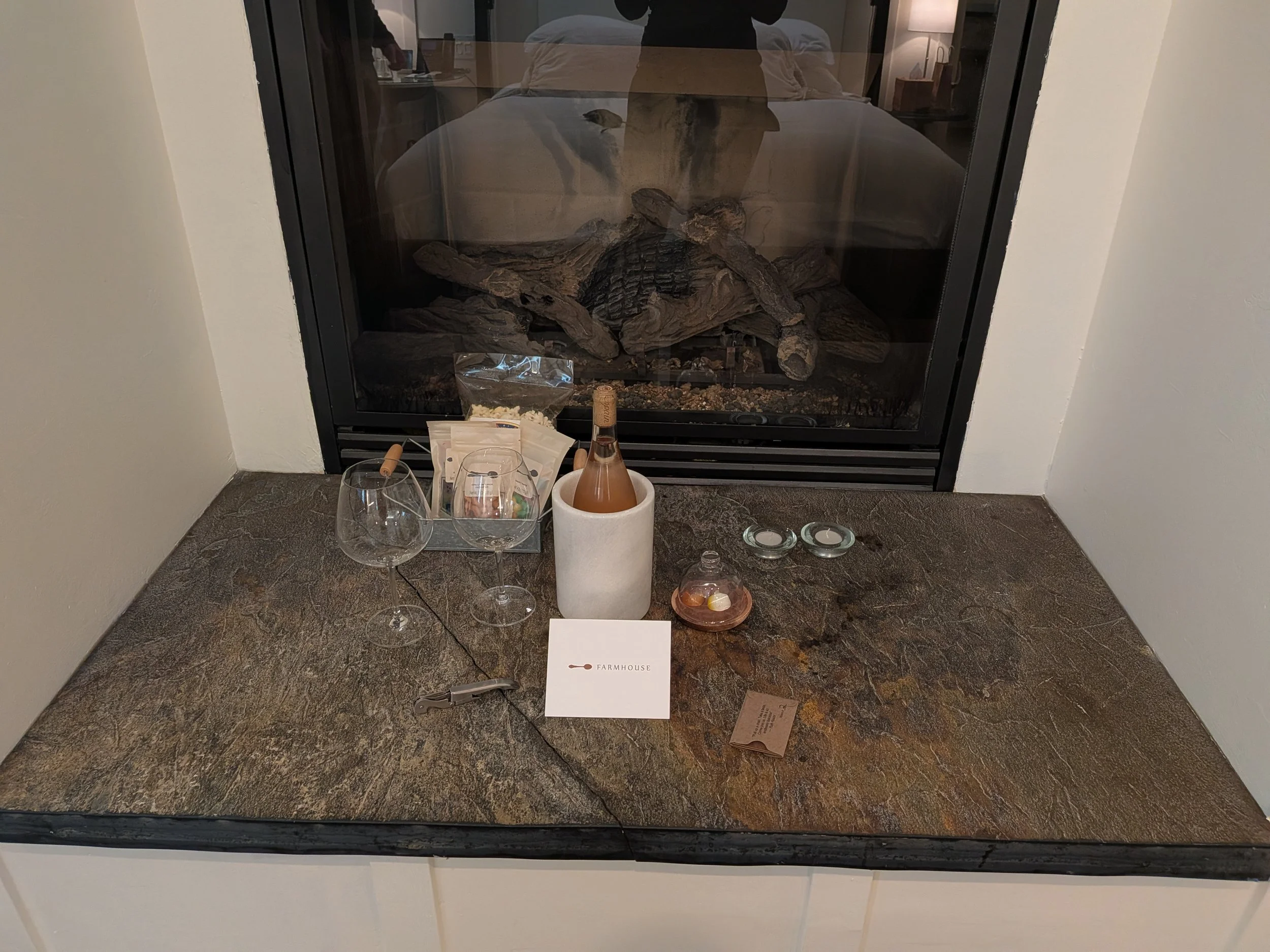 Snacks, wine glasses, wine bottle in front of a fireplace at the Farmhouse Inn in Forestville, California