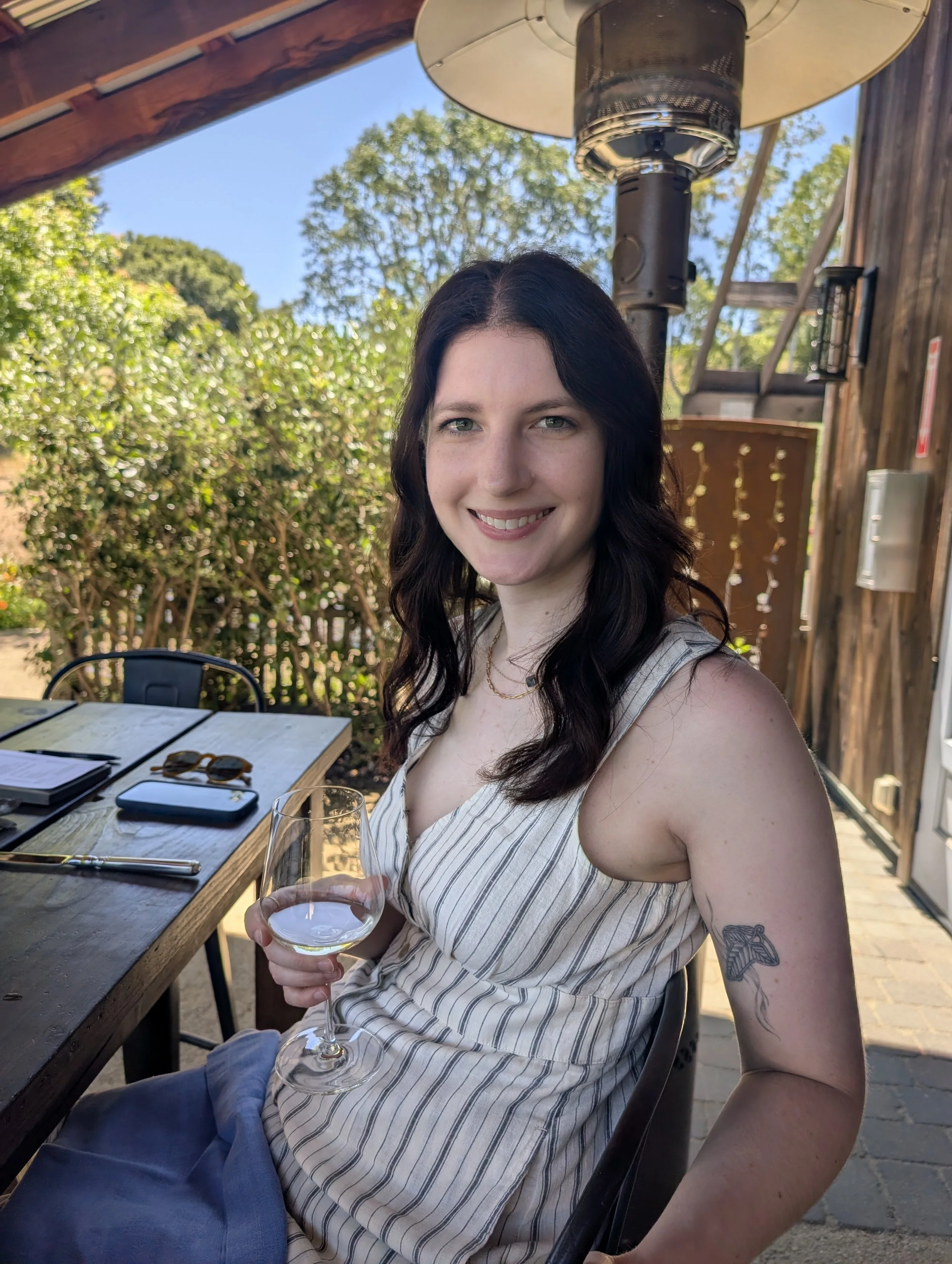 A woman smiling with a wine glass and trees in the background at Capo Creek Winery in Healdsburg, California