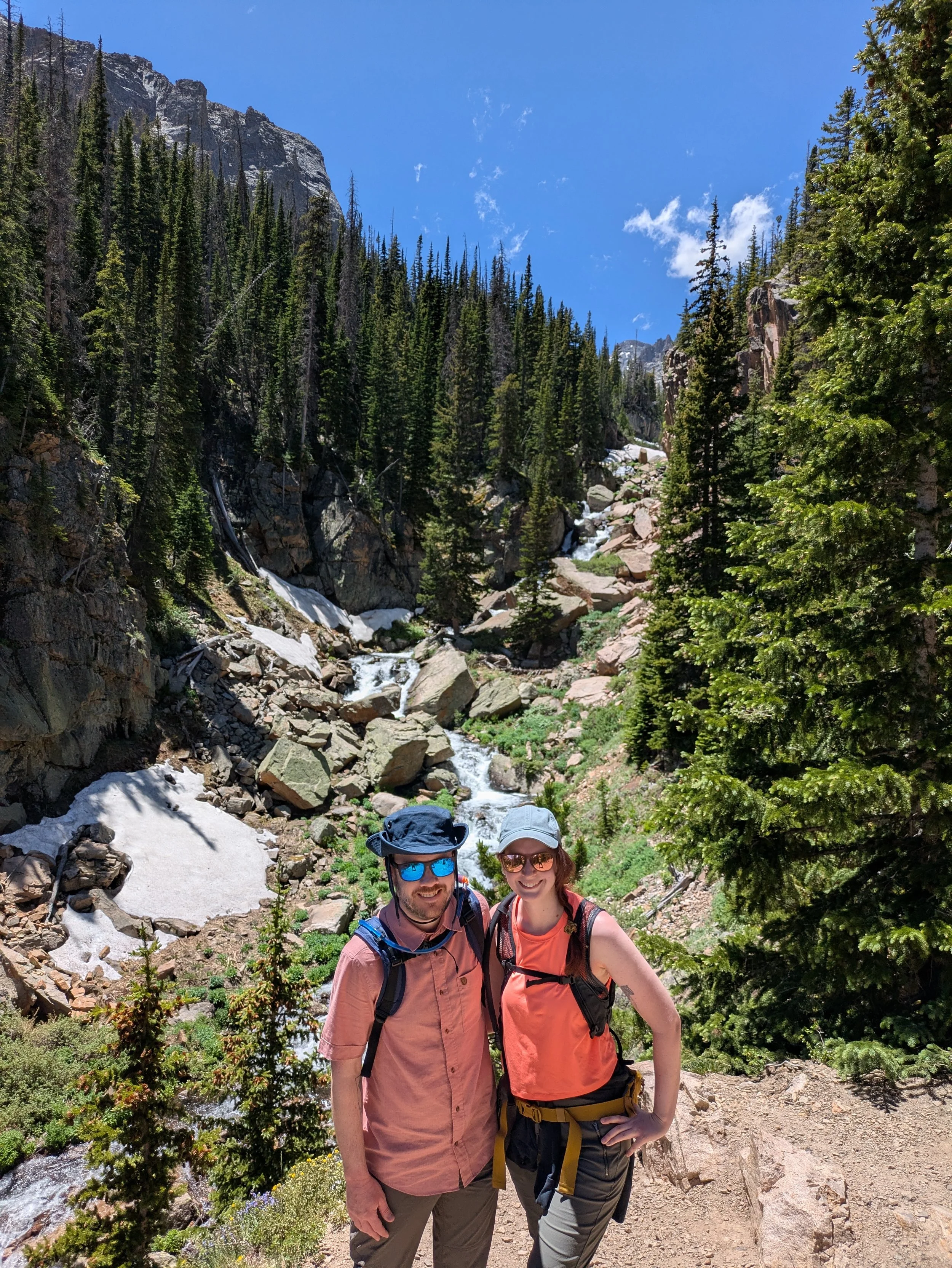 A hiking couple posing by stream in Rocky Mountain National Park